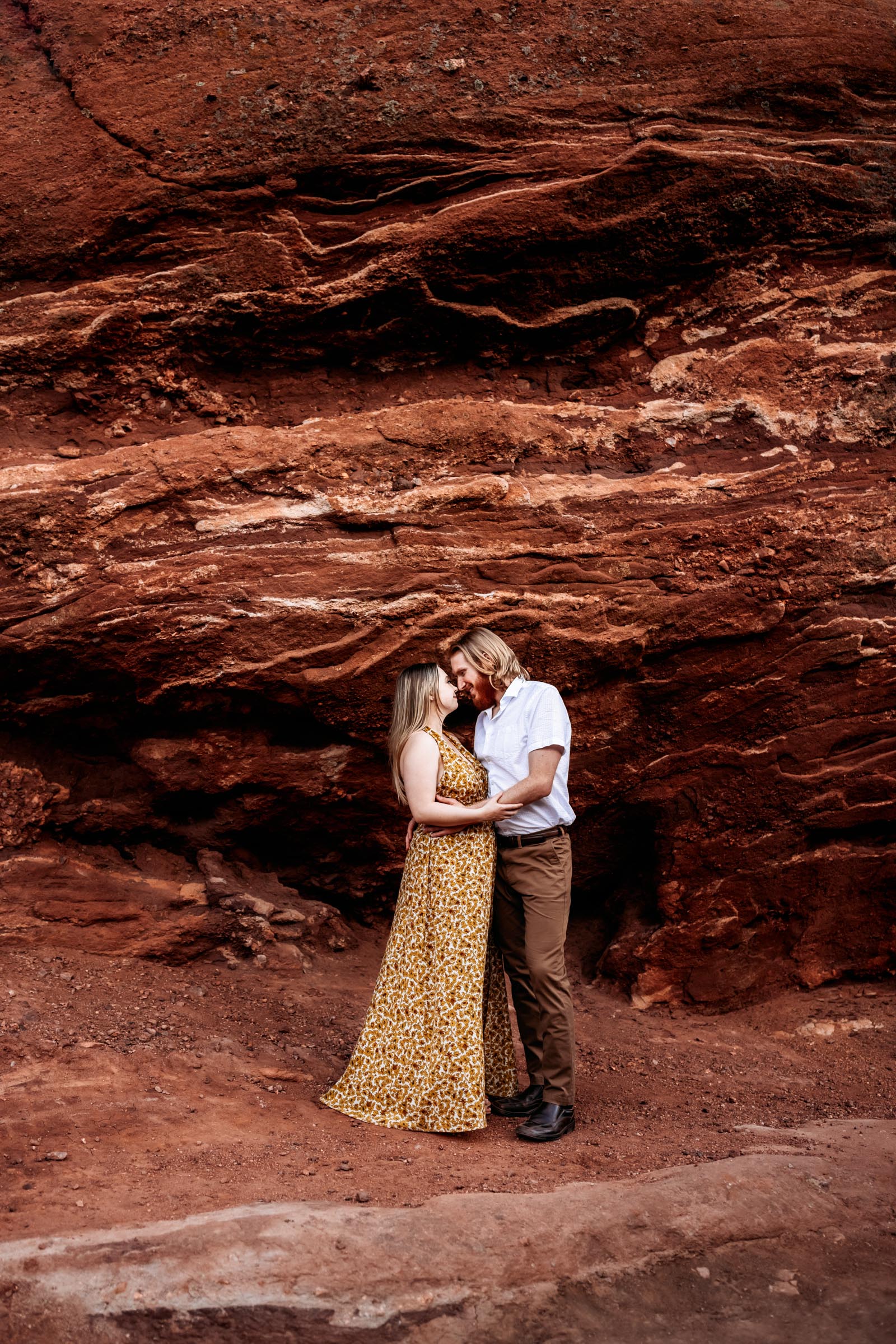 Couple standing in front of large red rocks