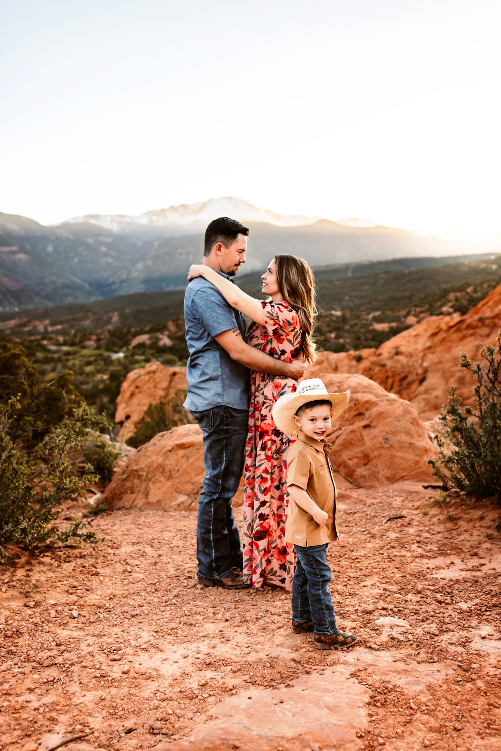 A family shares a heartfelt embrace, with their young son smiling in the foreground, at their spring photo session in Colorado Springs.