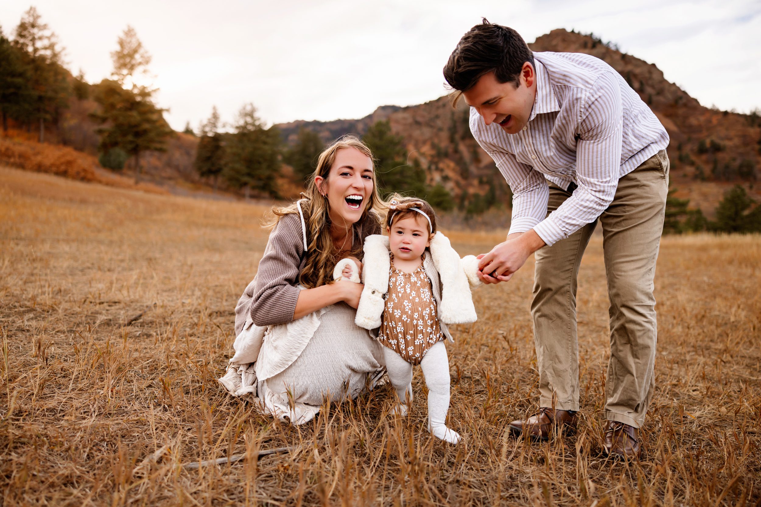 A father and mother lovingly admire their baby girl, capturing a beautiful connection in the heart of nature