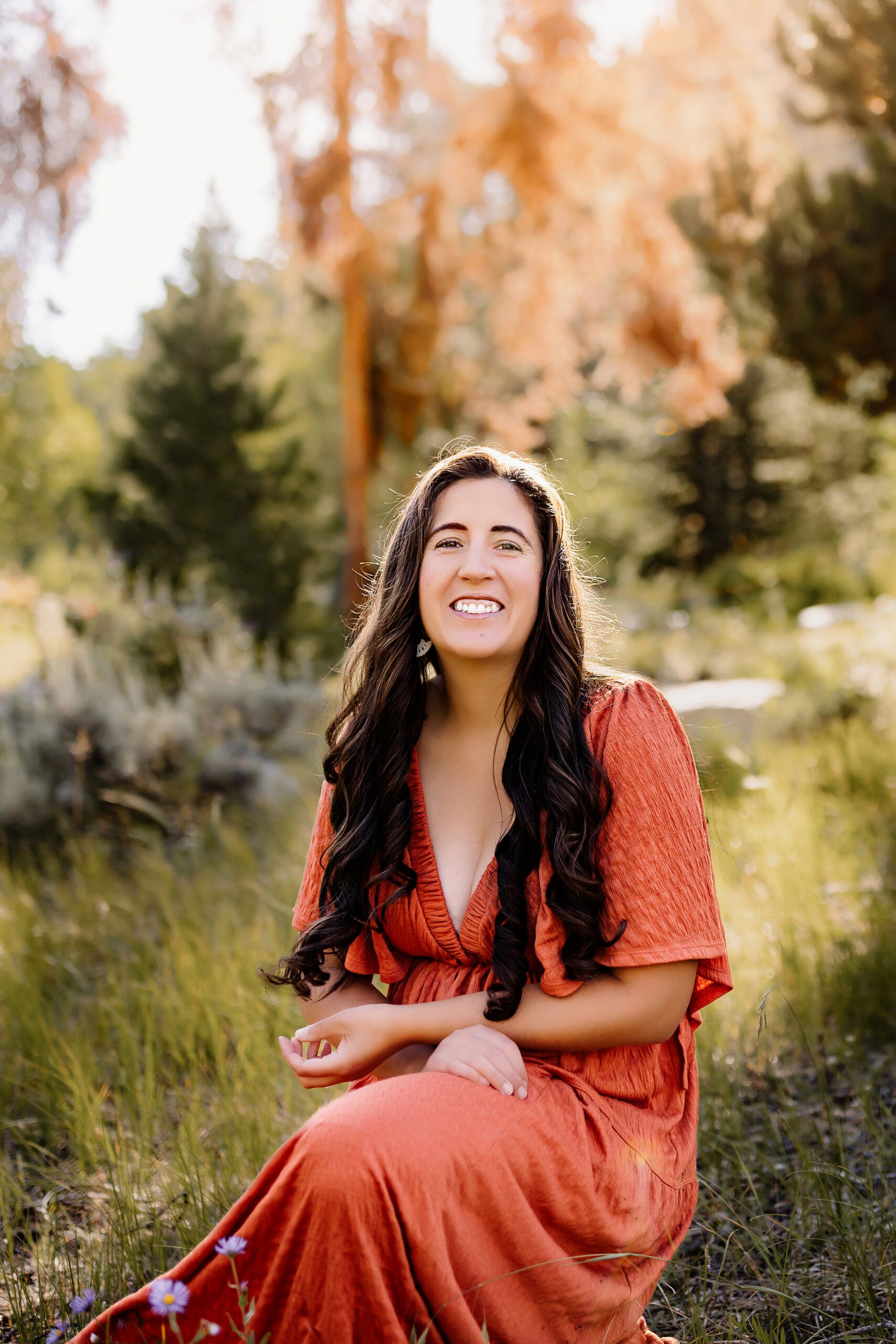 the photographer smiling at the camera in a natural setting with tall pine trees in the background