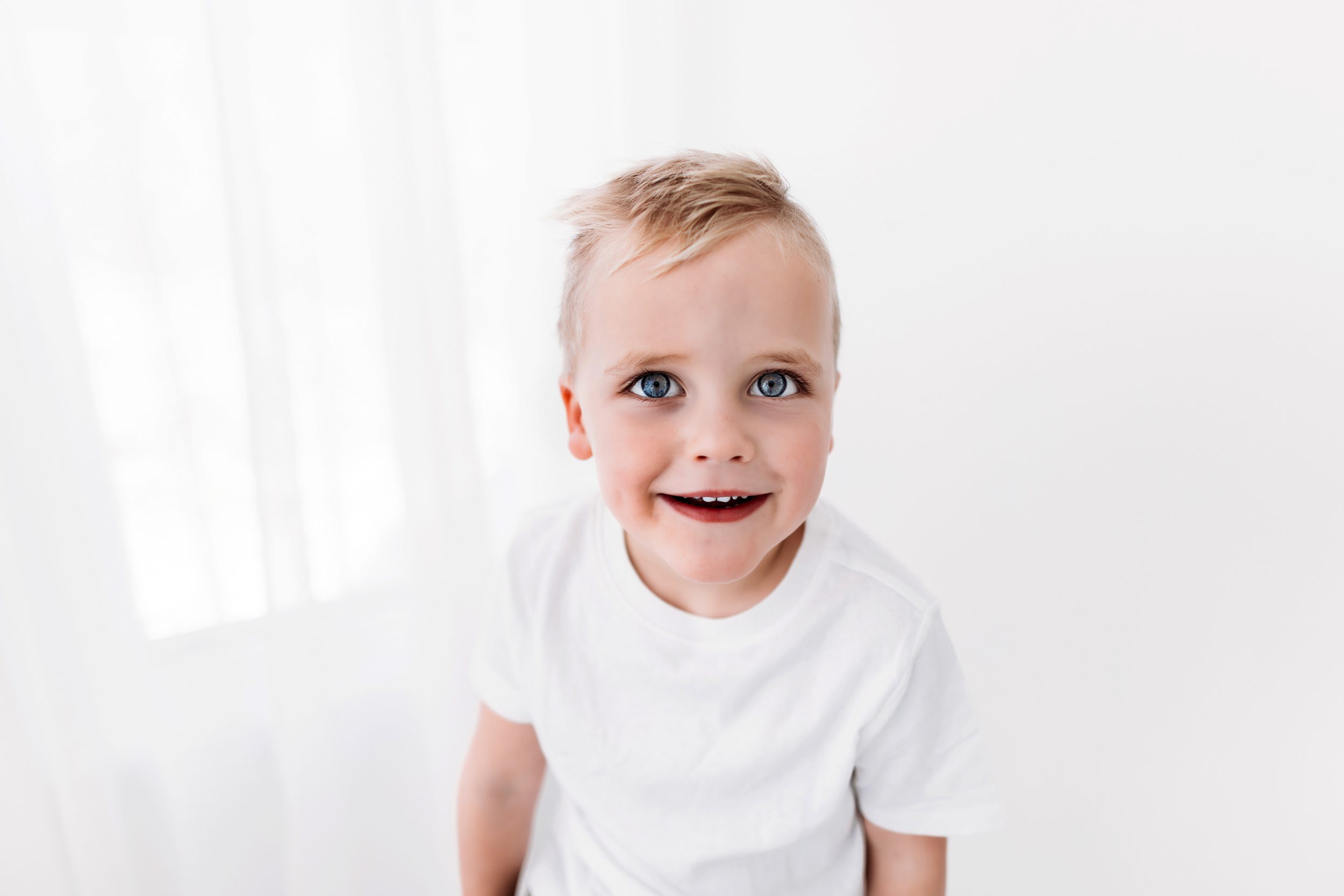 A close-up portrait of a little boy with bright blue eyes.