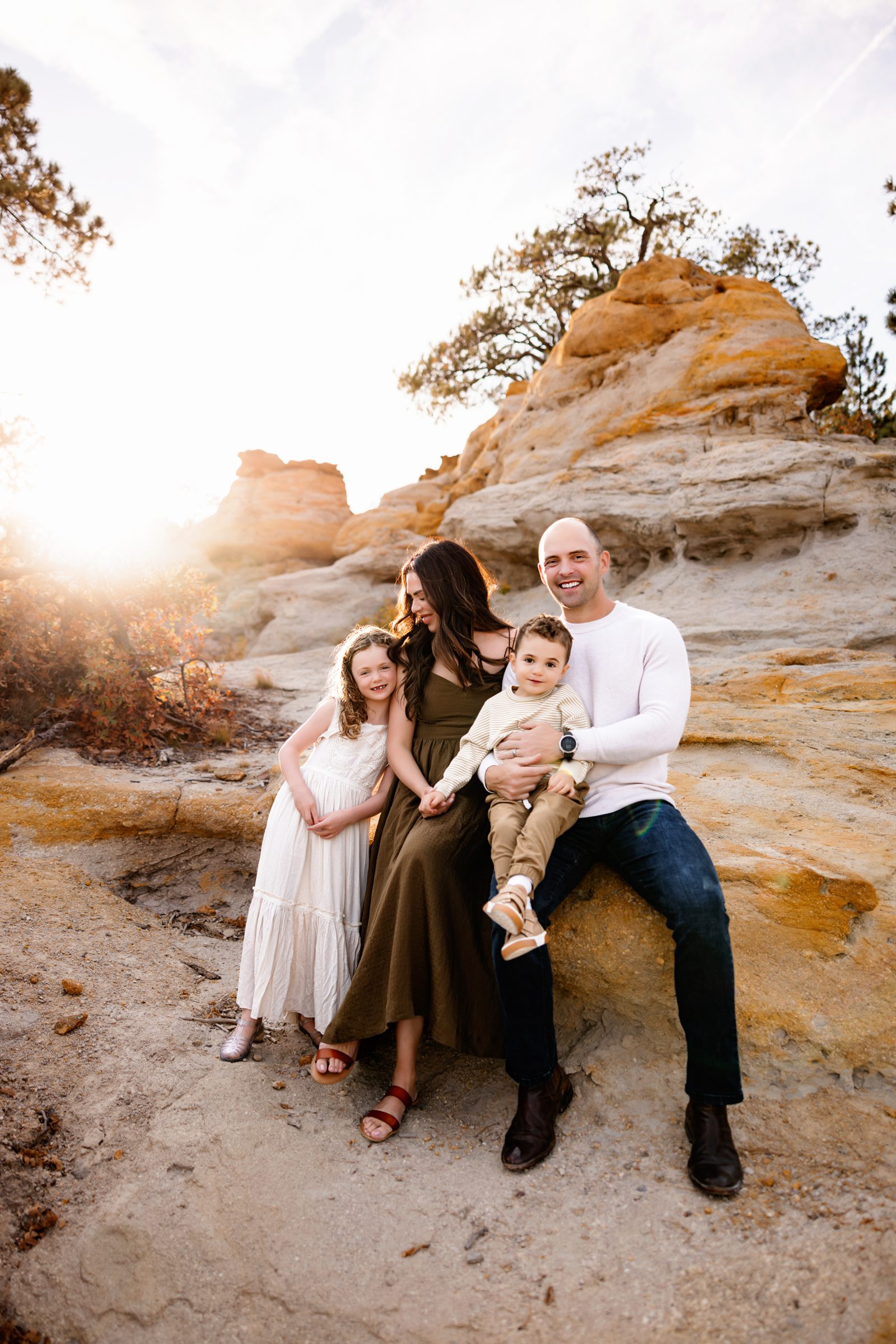 A relaxed family moment captured in a Colorado Springs Outdoor Photography Session, as parents and children sit against the warm sandstone rocks