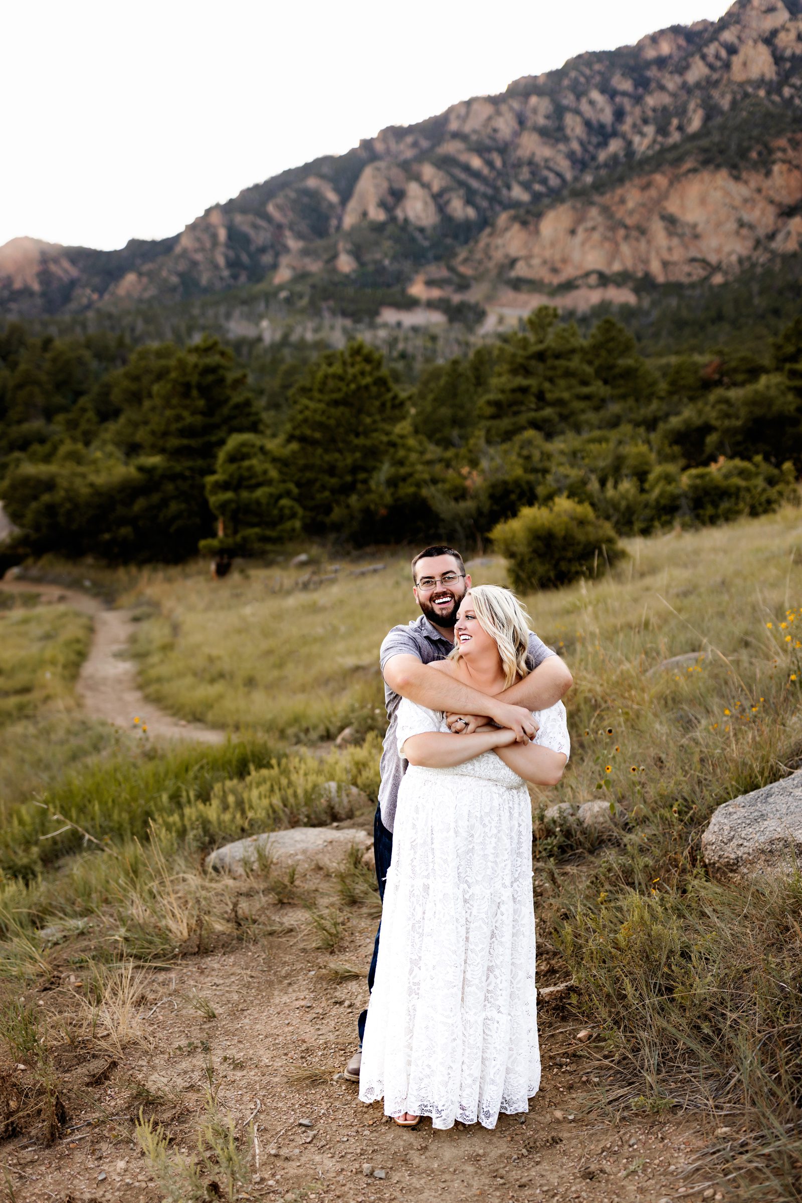 A romantic moment of a couple enjoying each other’s company, framed by rolling green hills and stunning mountain views