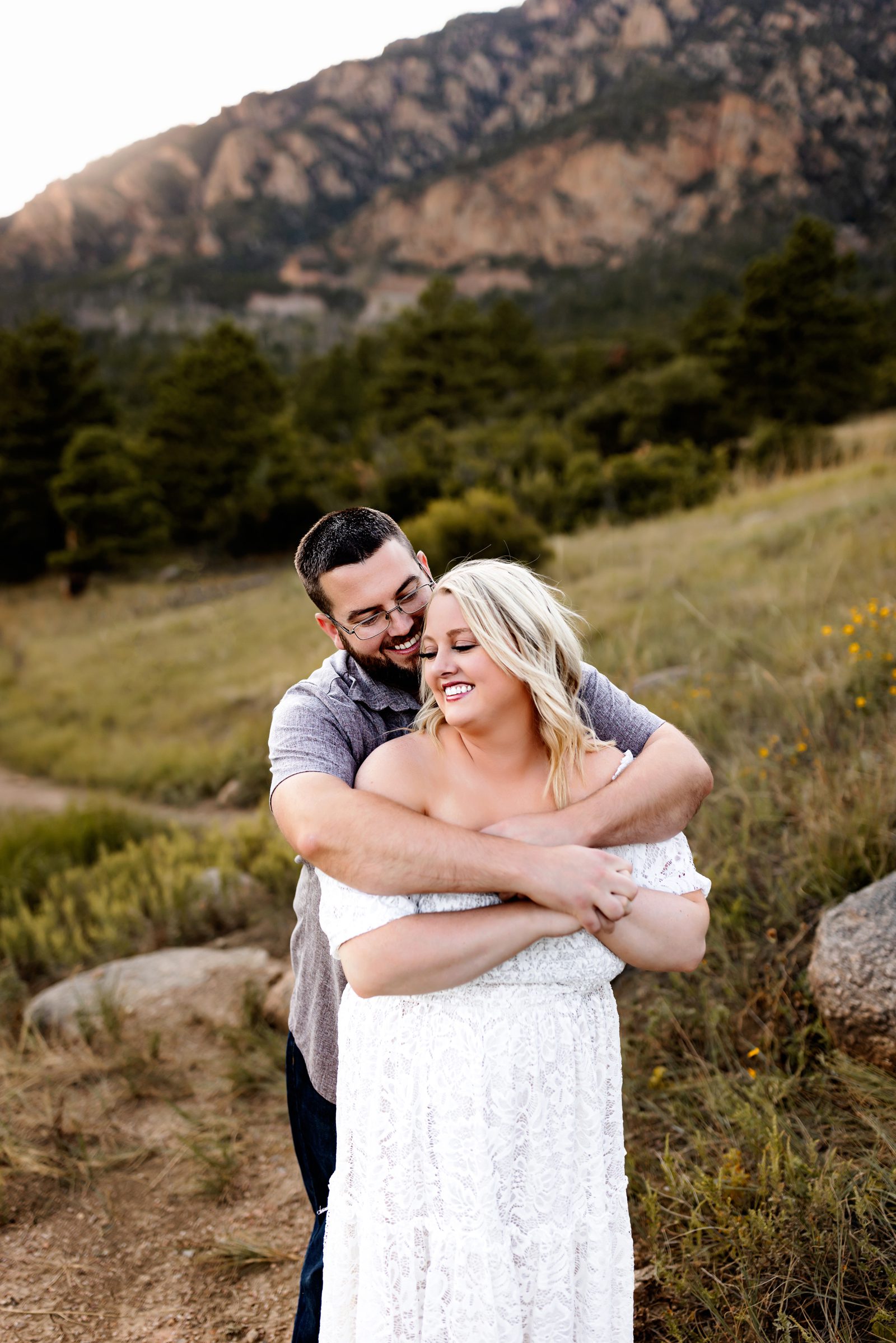 A man wraps his arms around his partner, both laughing and enjoying a heartfelt moment