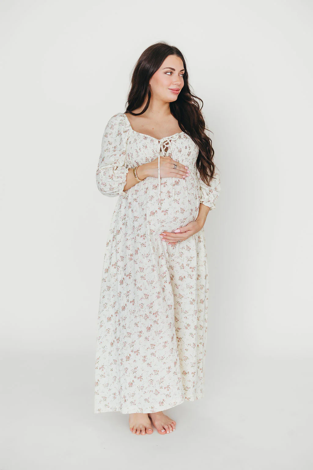 A pregnant mama wearing a white dress with a subtle floral pattern