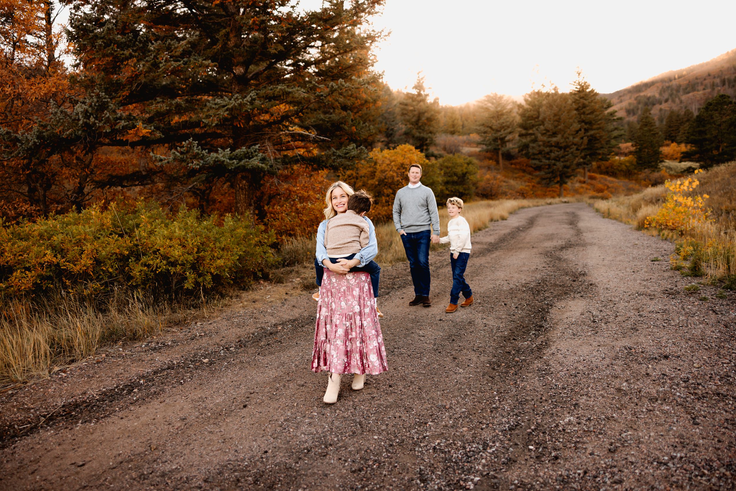 Mother carrying toddler while walking ahead of family during their Fall Family Mini Session.