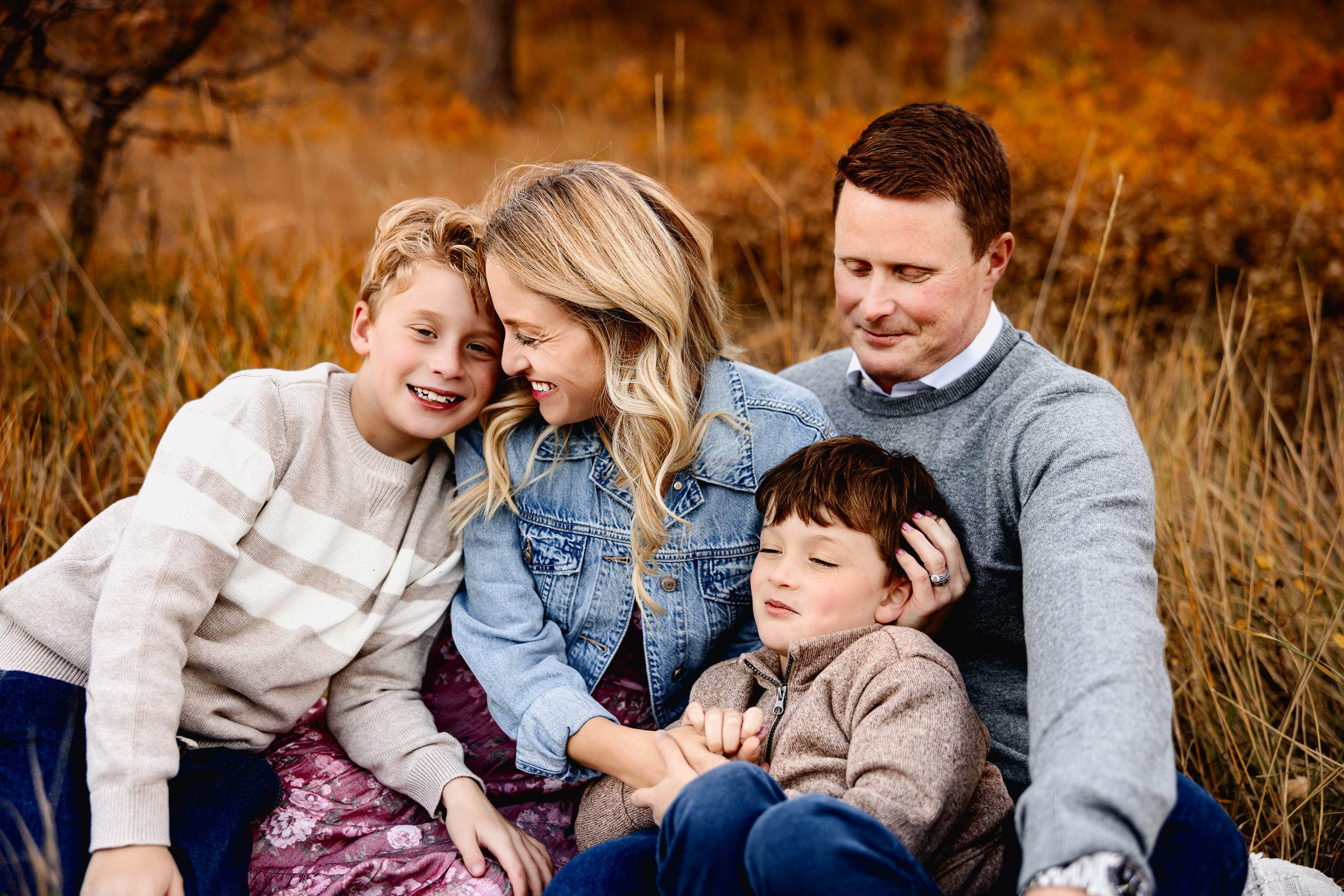 Close-up of parents and two boys smiling and snuggling 