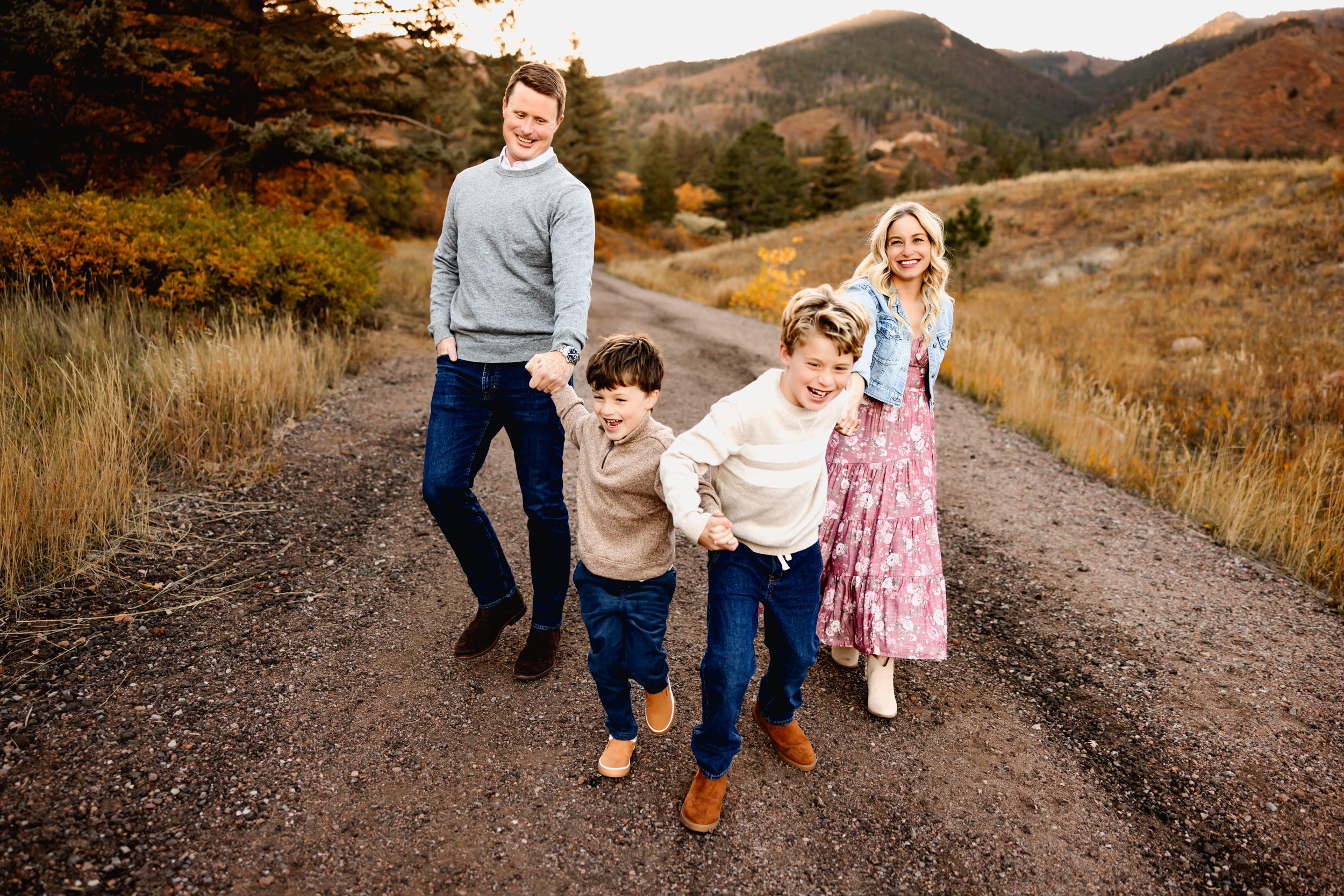 Joyful moment as family of four walks and laughs down a trail lined with fall colors.