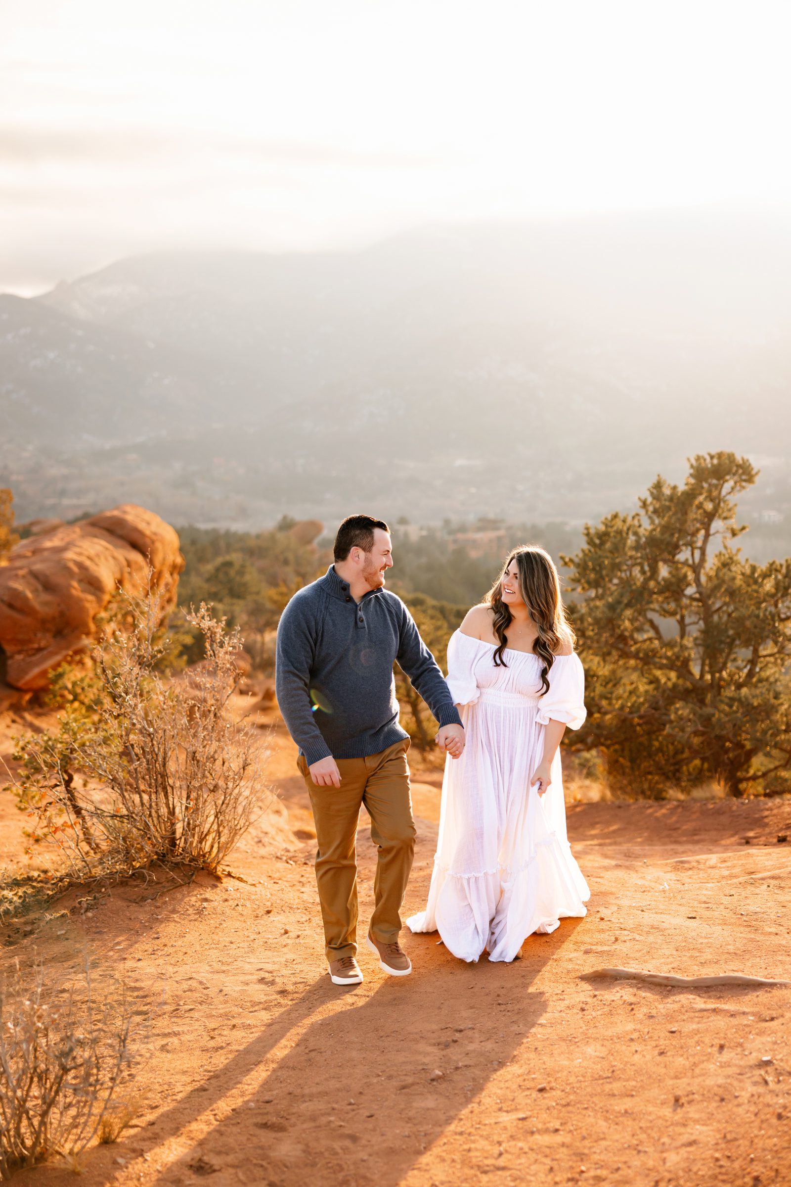 A couple walking together at Garden of the Gods with the glowing sun behind them