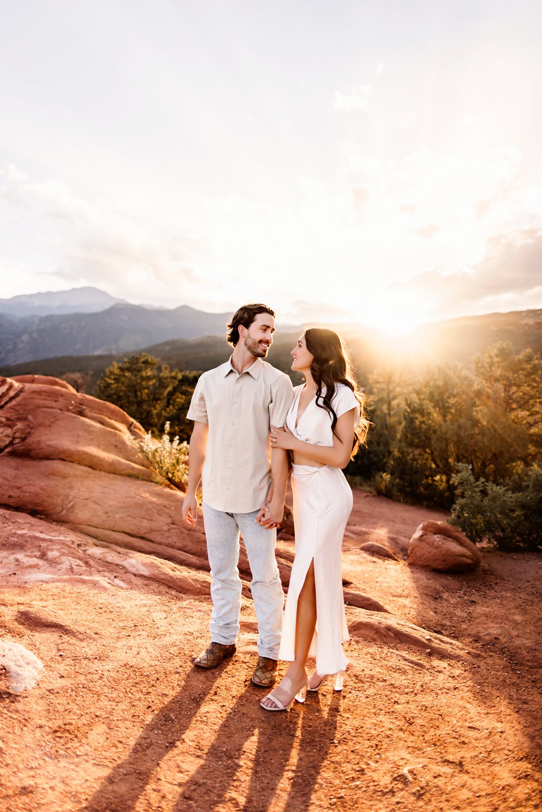 Playful walk through the red rocks during a sunset couples session at Garden of the Gods.