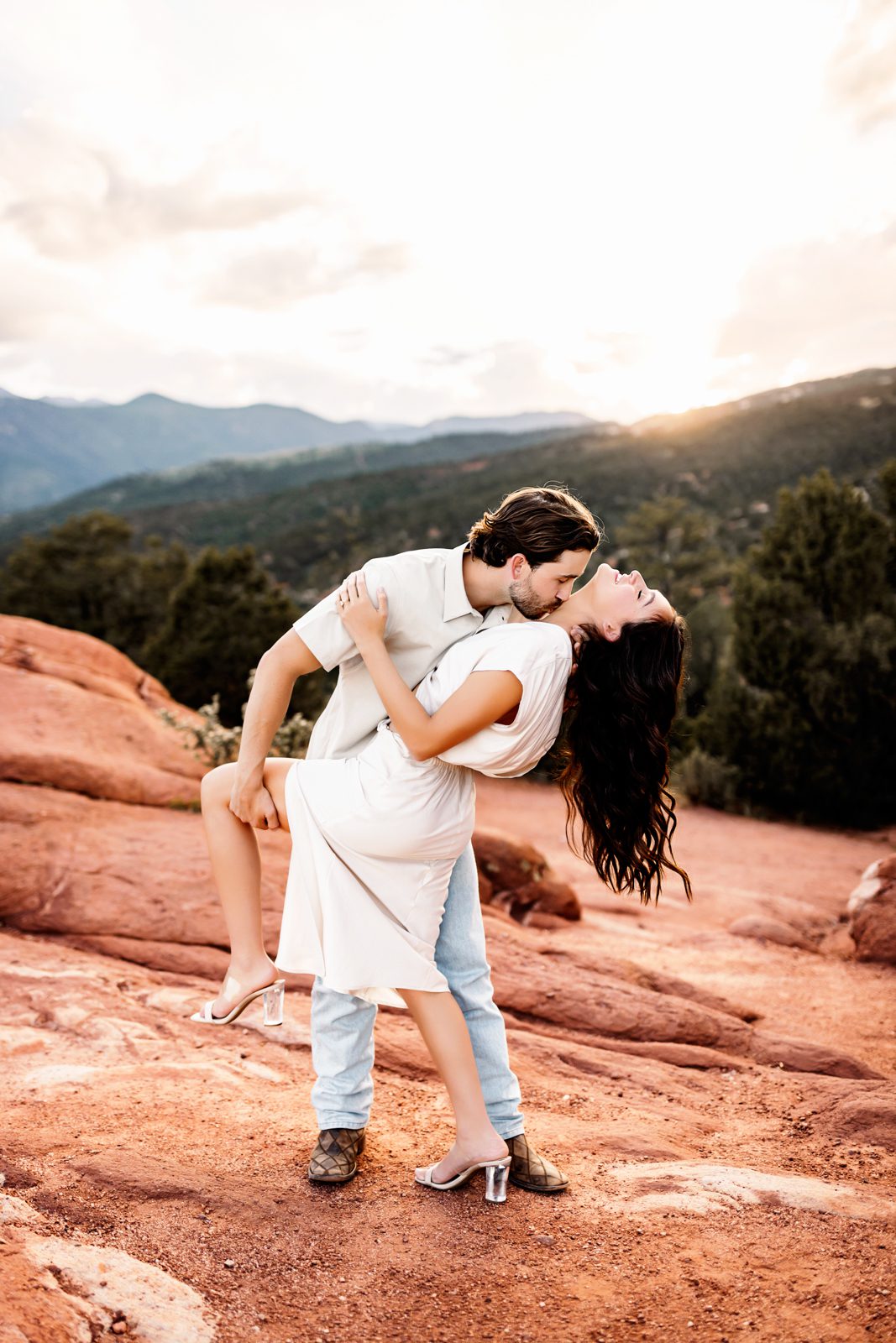 Playful dip kiss with golden hour light and red rock landscape in the background.