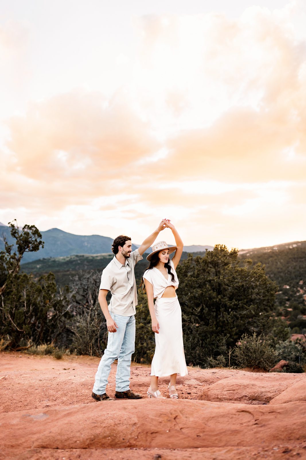 Playful dance captured during a couples session at Garden of the Gods under a dreamy sunset sky.