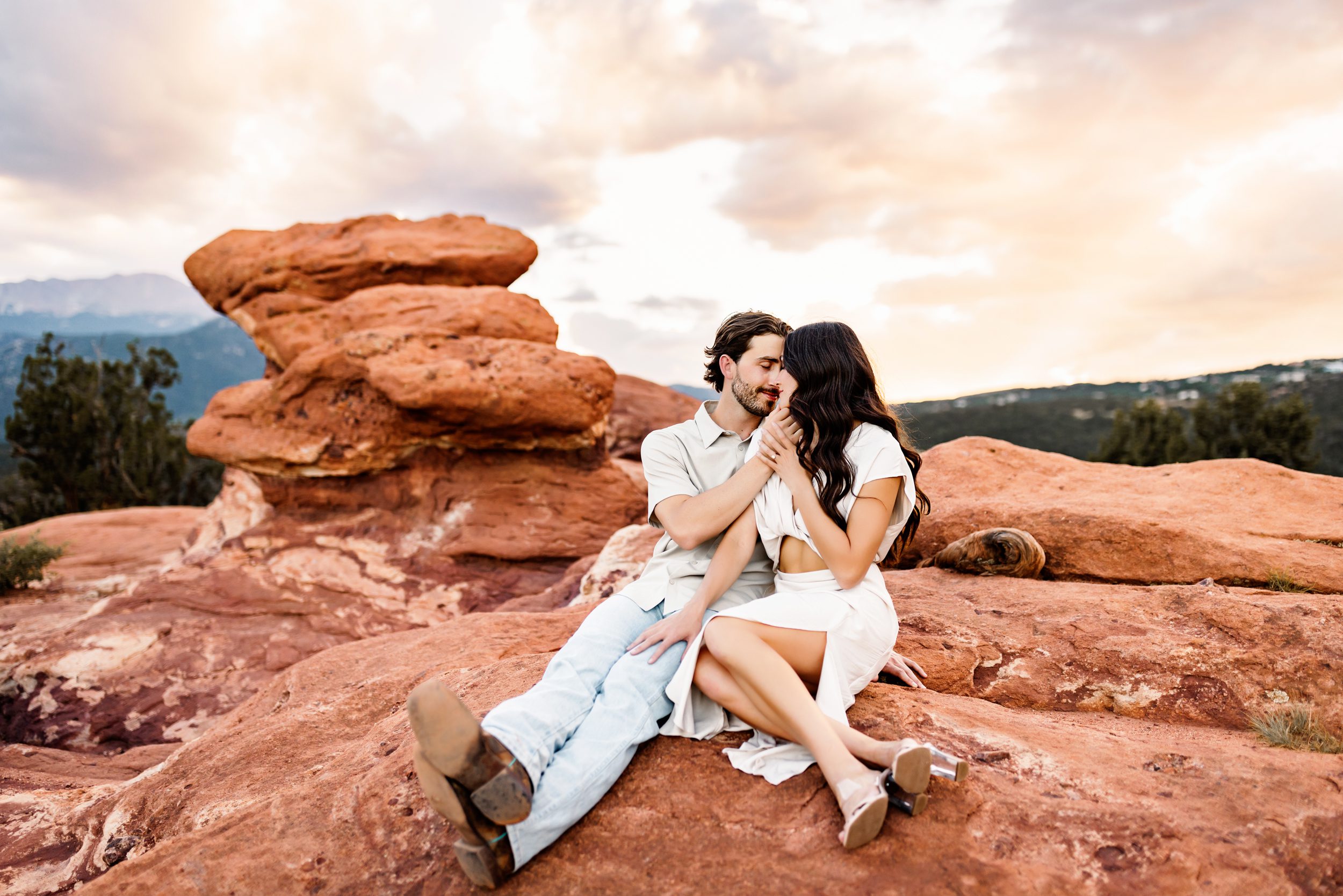 Couple sharing a sweet moment as the sun sets over the red rocks and forested hills of Colorado.