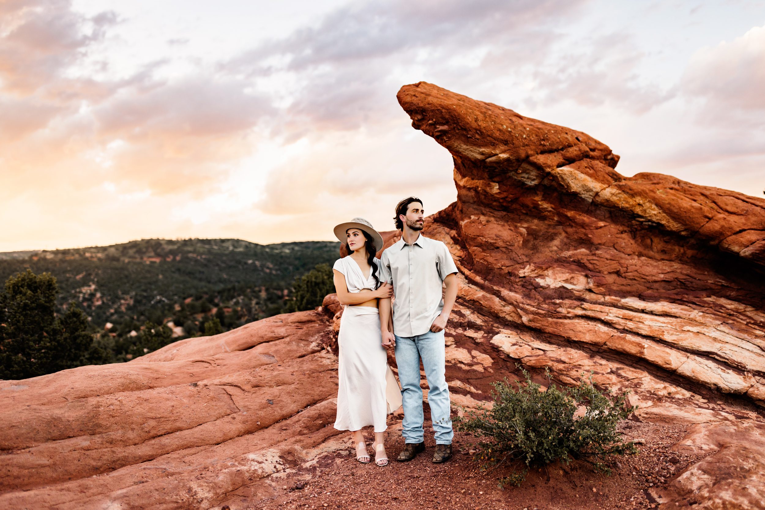 Stylish couple posing against dramatic red rocks and moody skies at a scenic Colorado location.