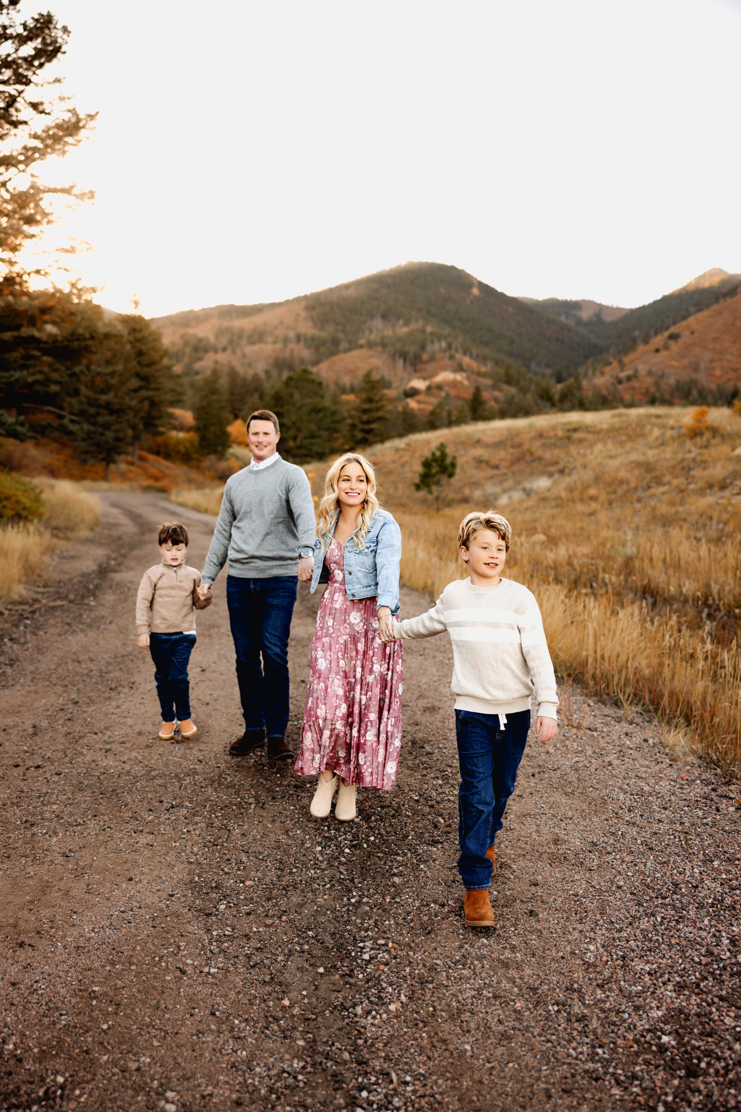 Family of four walking hand-in-hand down a mountain trail 