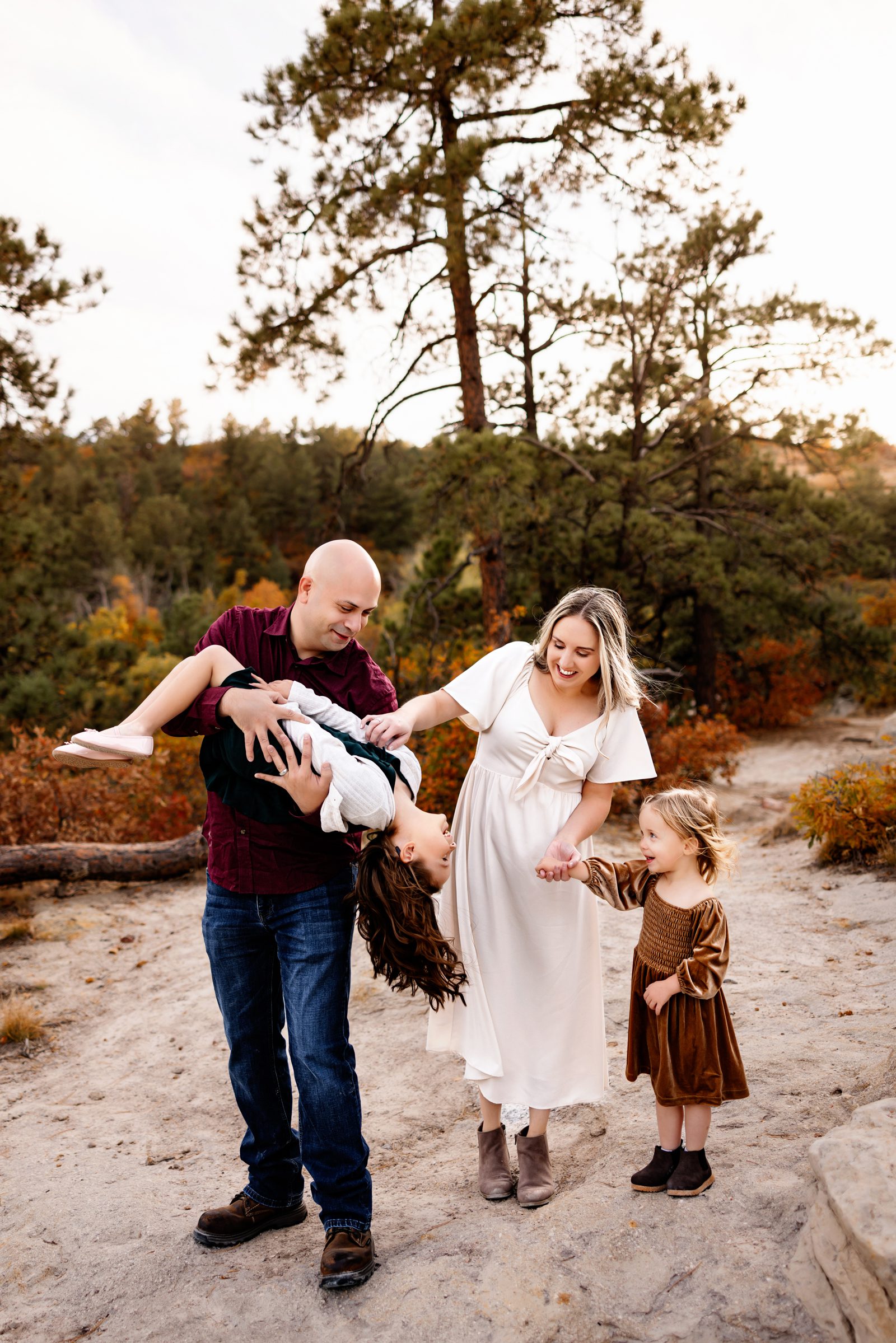 Parents and children enjoy a playful moment while exploring scenic sandstone formations and fall trees in Colorado.