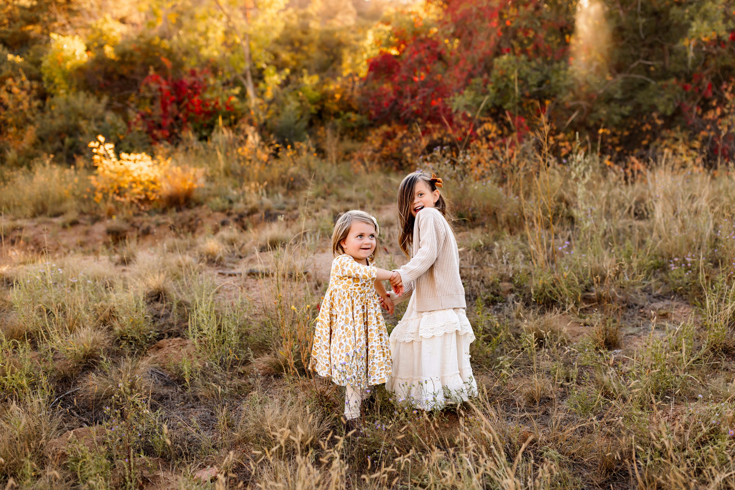 Sisters playing in the golden grass during a fall foliage session in Colorado Springs.