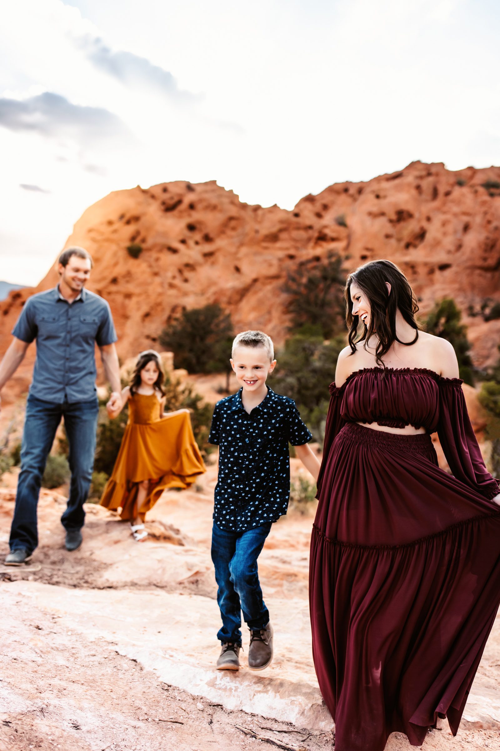 Candid moment during a Family Adventure Session as a family of four walks together across the red rock terrain.