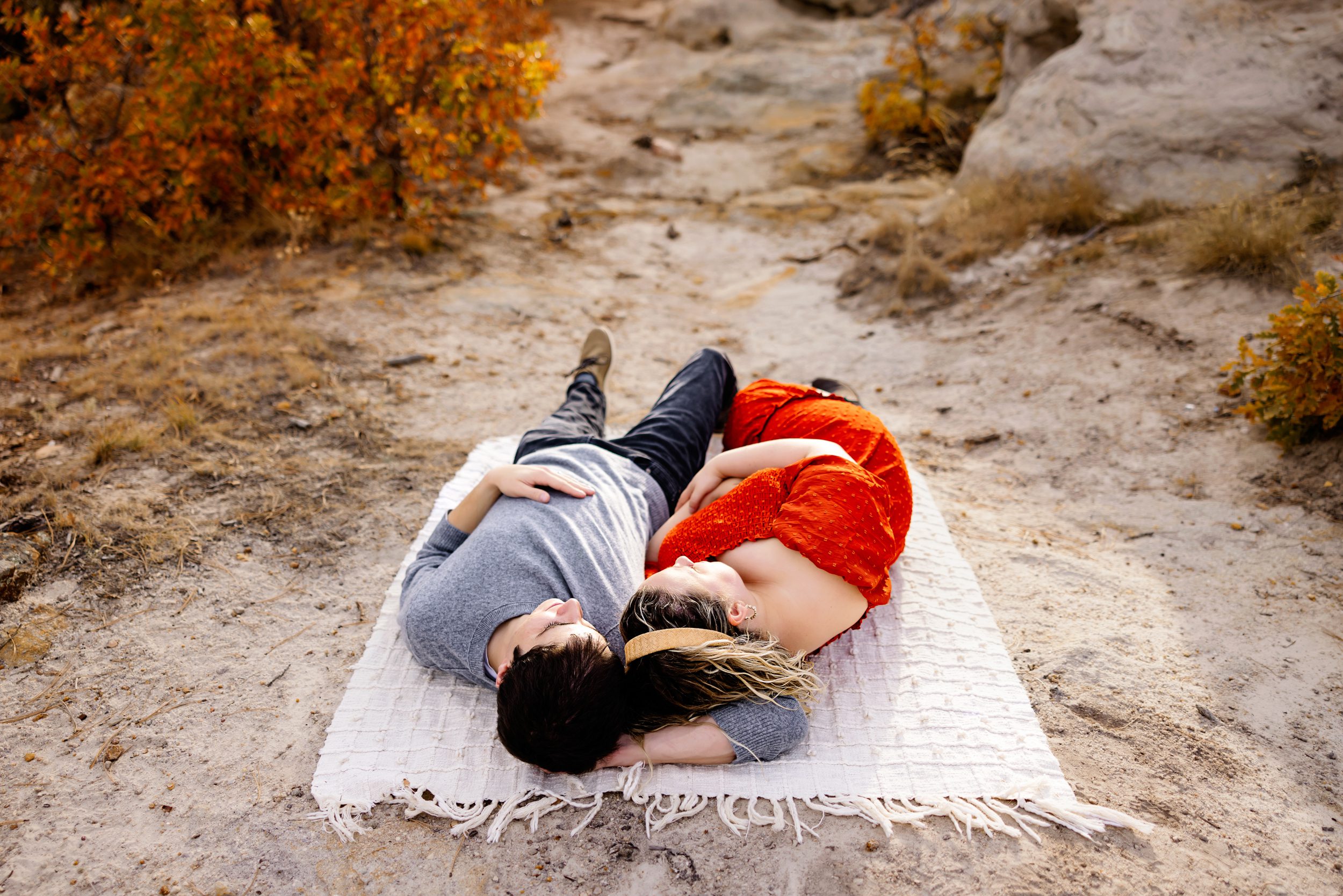 A collage of six joyful moments from a pregnancy announcement photo session featuring a couple in fall colors holding ultrasound images, cuddling, and walking through a rocky Colorado landscape