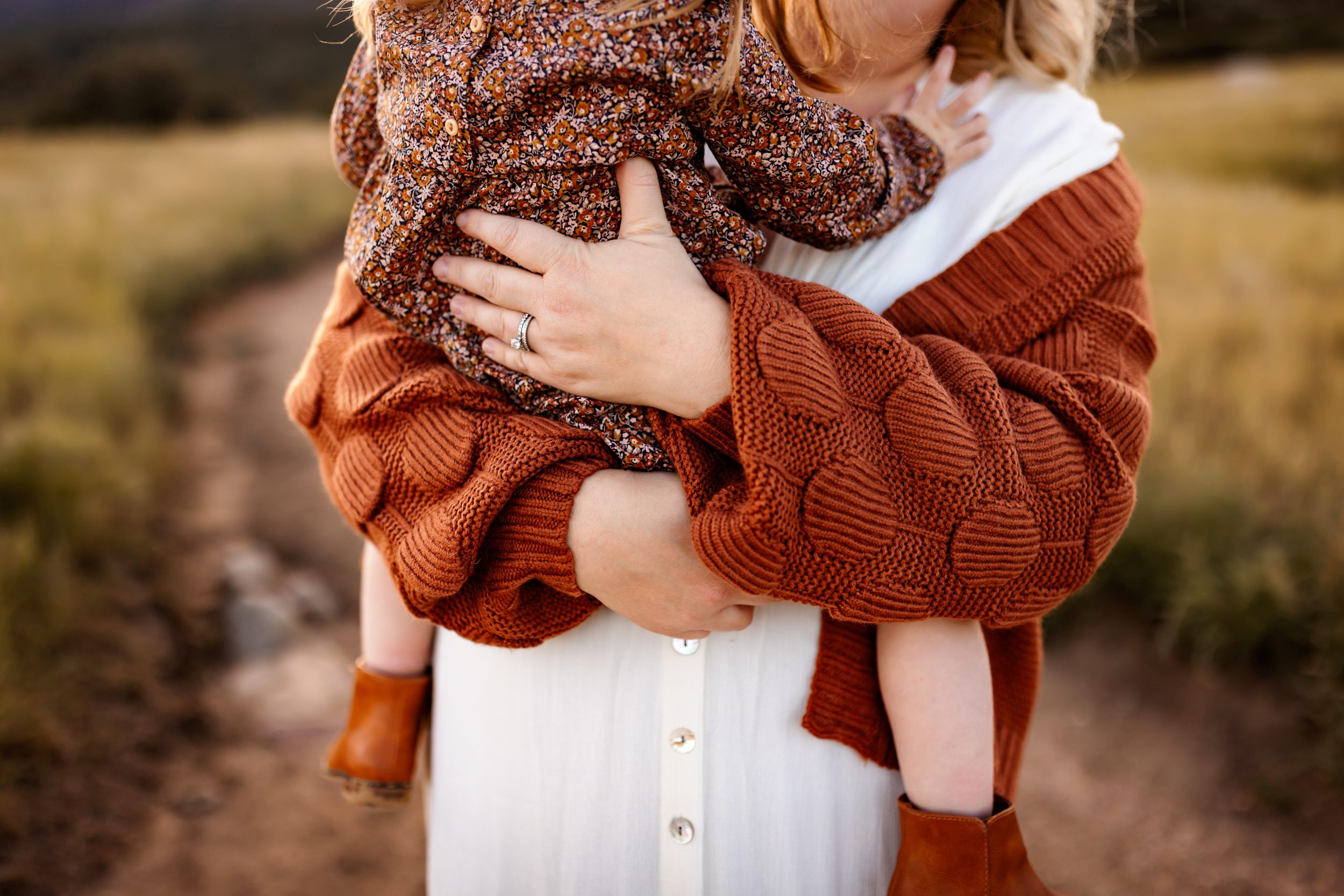 a mom snuggling her baby wearing a floral romper in warm autumn tones