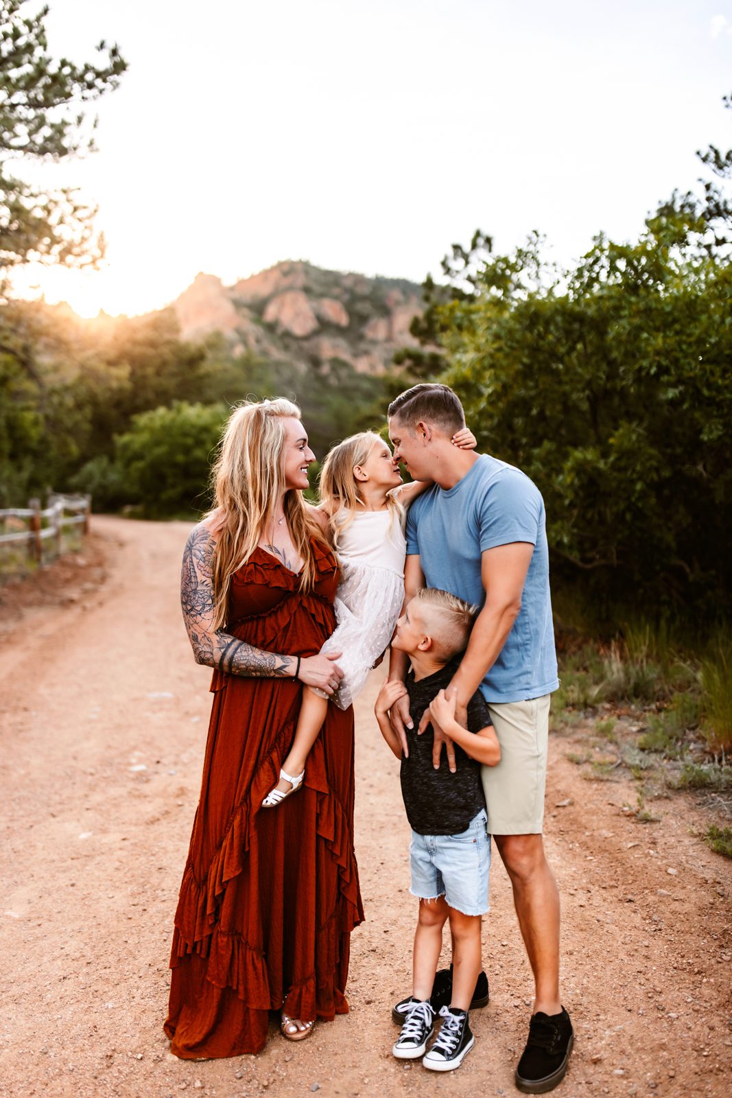 Sweet family moment with mom and daughter exchanging kisses while dad and son smile playfully