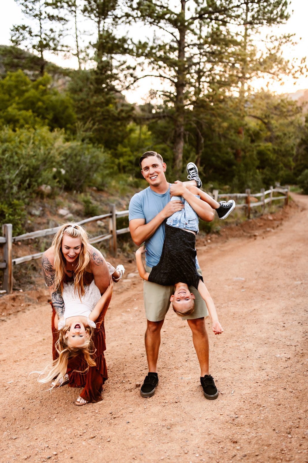 Playful parents hold their kids upside-down, enjoying a joyful moment outdoors