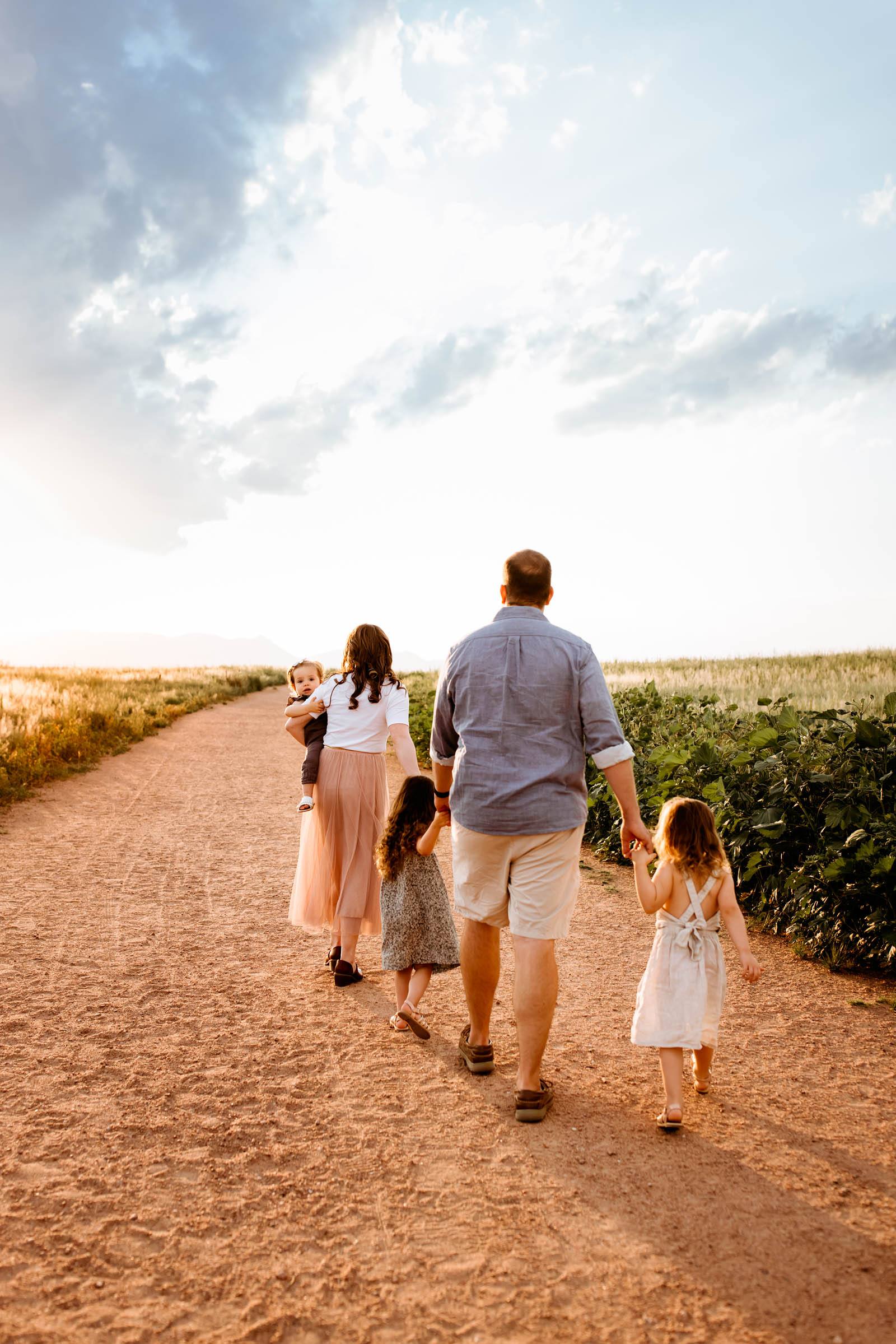 A family strolling down a picturesque path at golden hour, enjoying their Colorado Springs Summer Session.