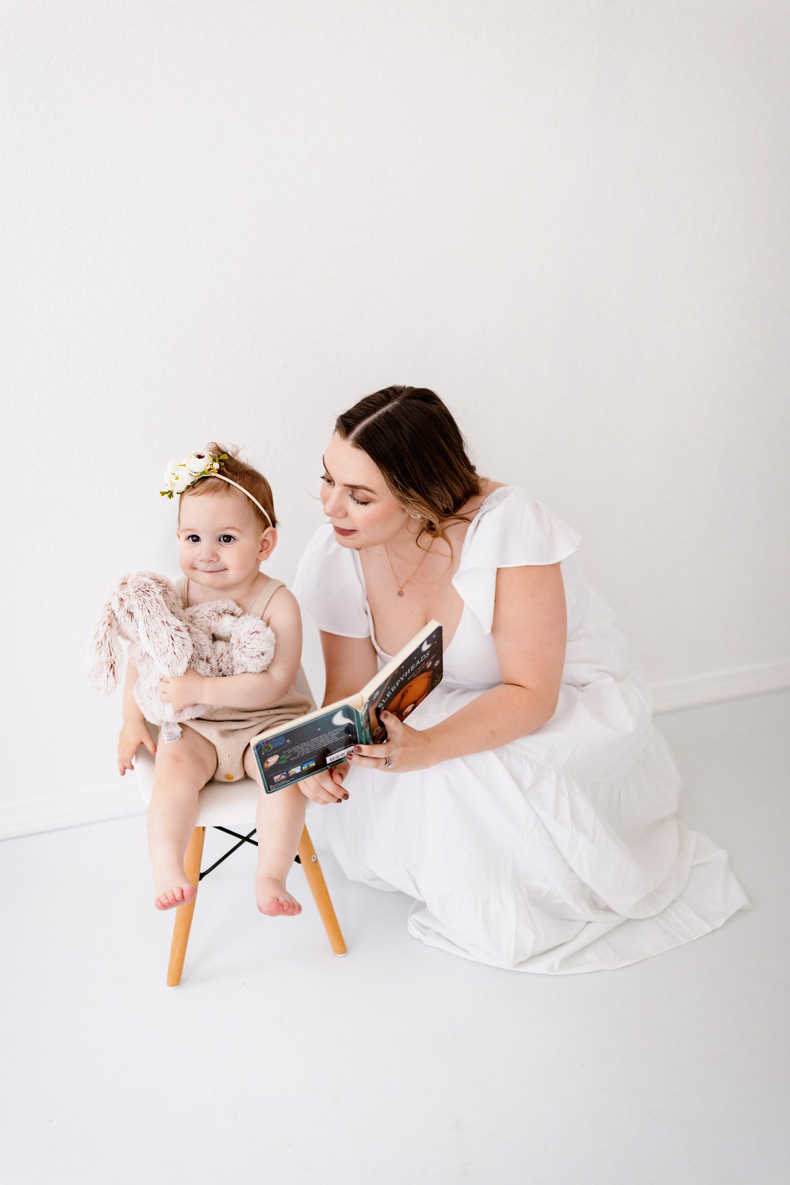 One Year milestone photos in Colorado Springs of a mom reading to her toddler while they sit together with a stuffed bunny