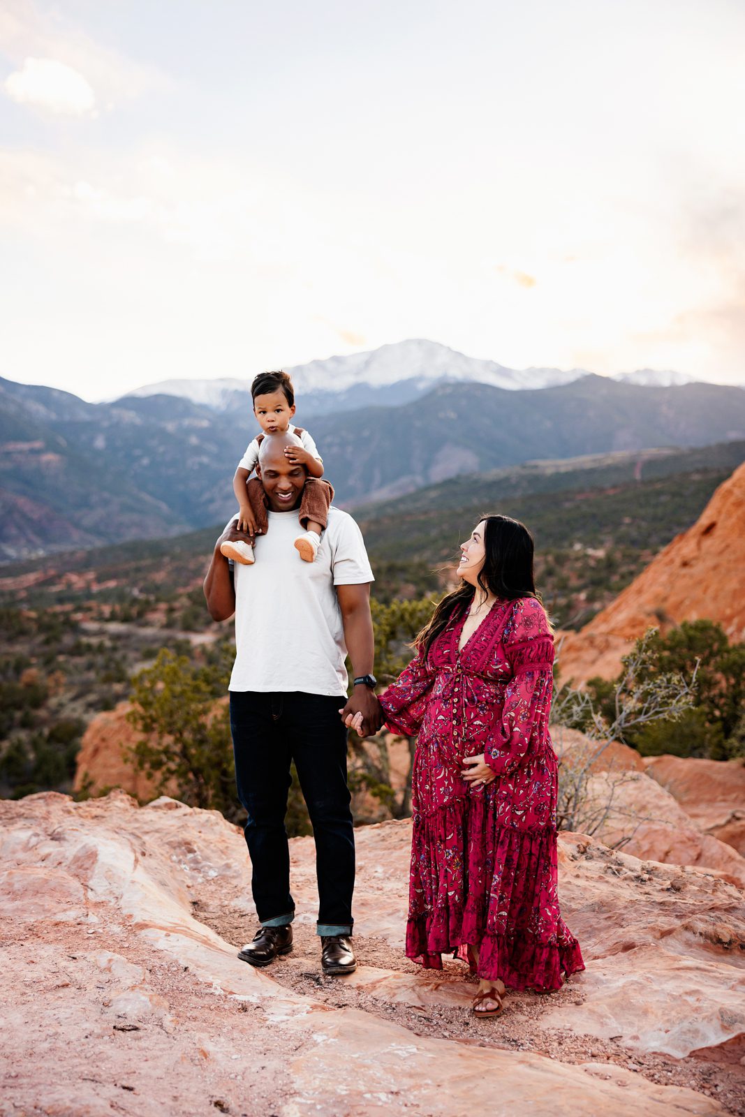 when to take maternity photos colorado with a couple walking hand in hand as dad carries toddler on his shoulders