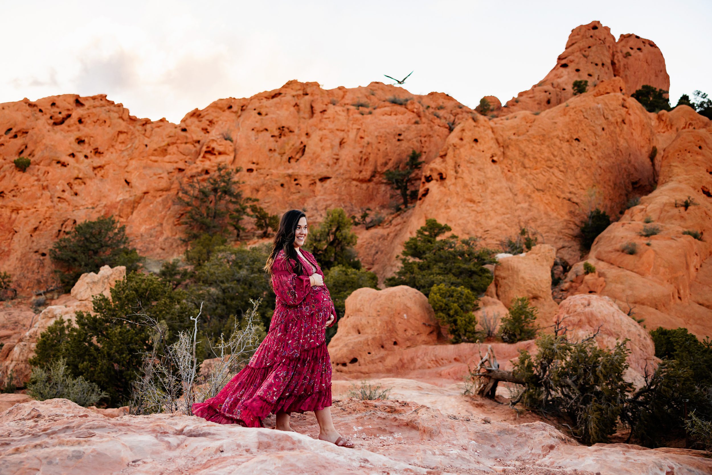 when to take maternity photos colorado showing a glowing expectant mother standing among red rock formations