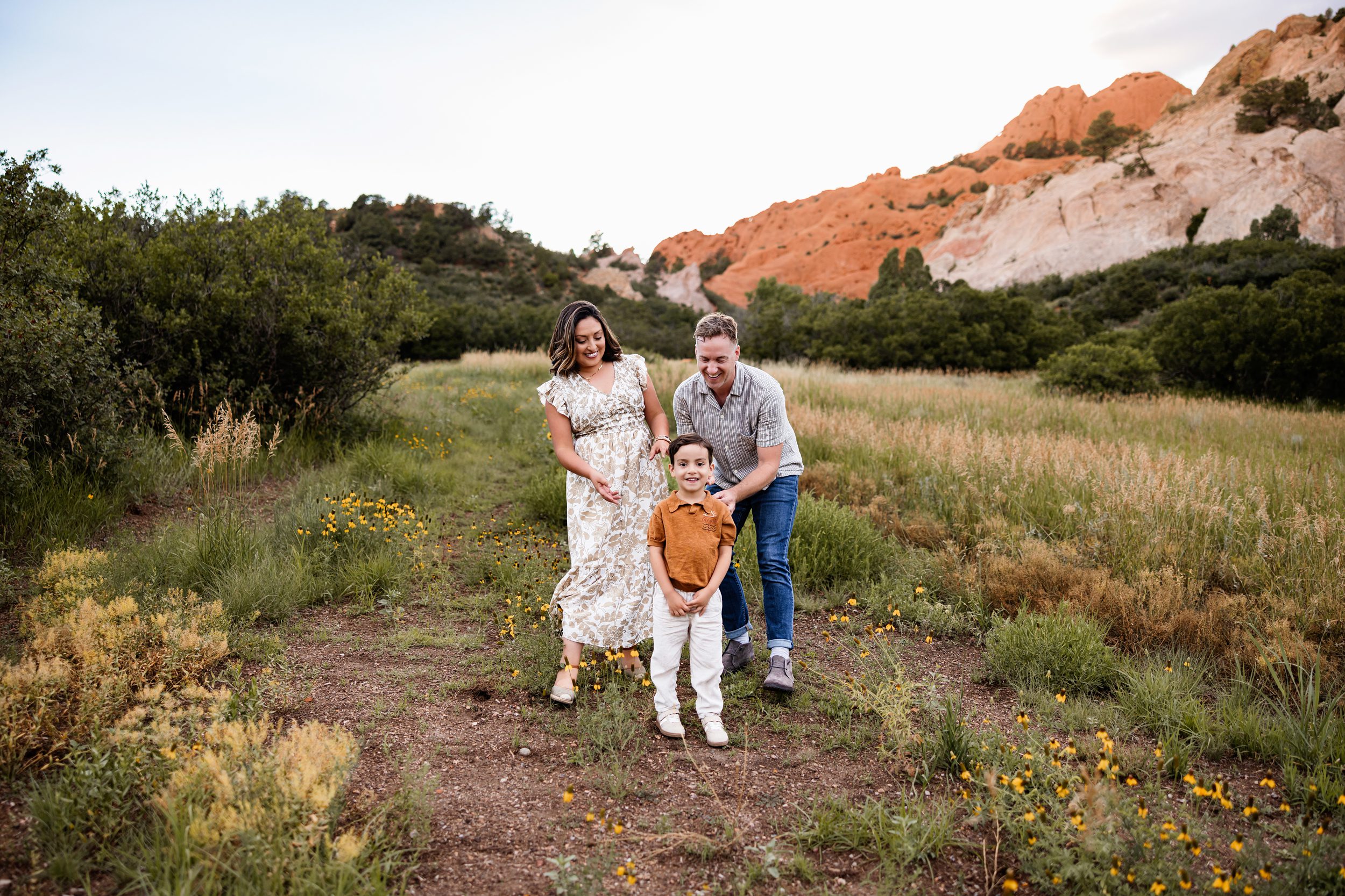 Family standing together in a meadow with yellow wildflowers and Garden of the Gods red rock formations in the background