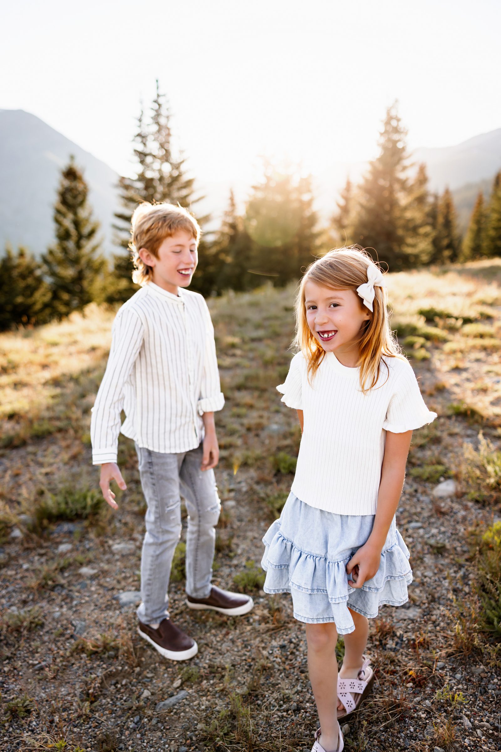 Two kids smiling and playing together in golden mountain light during a summer photo session in Breckenridge