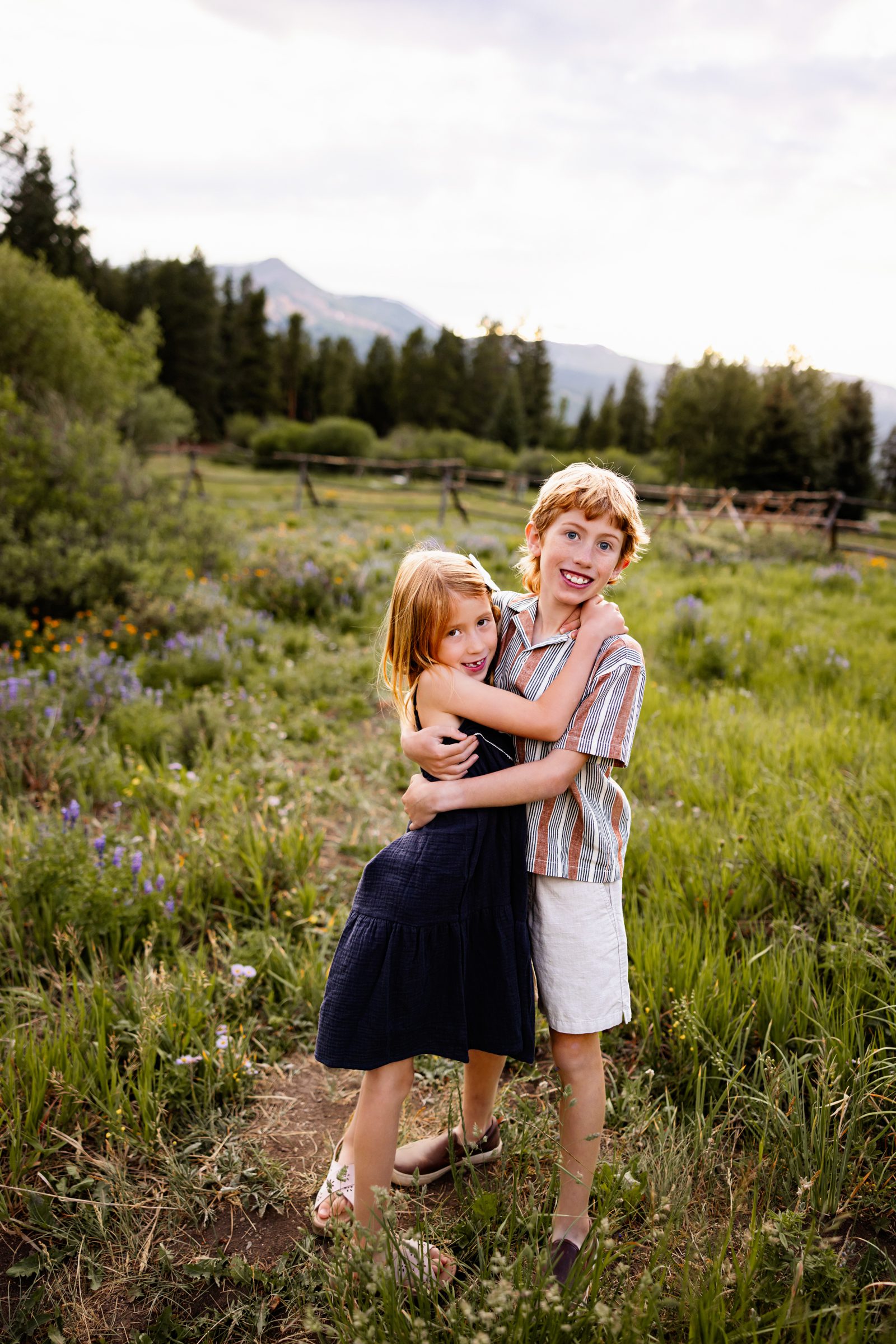 Breckenridge wildflower family photos of siblings hugging and smiling in a lush meadow at sunset