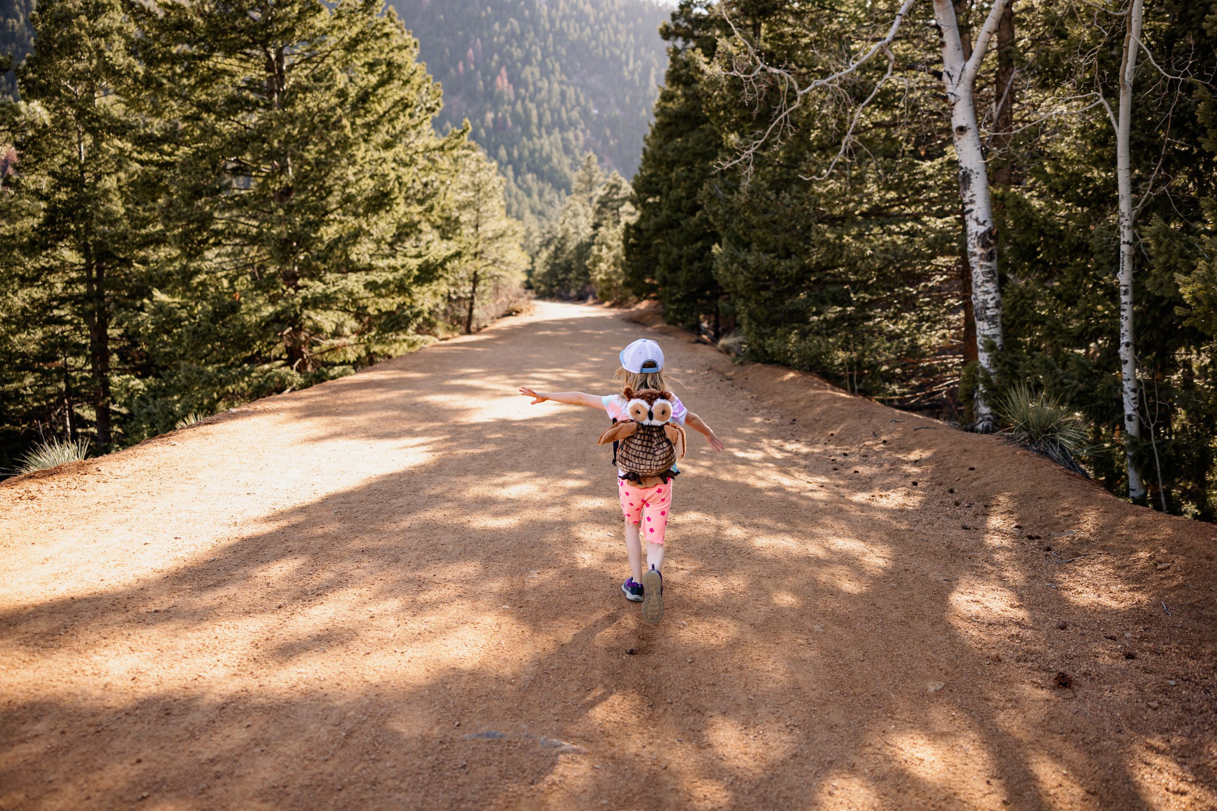 Little girl exploring a scenic dirt path surrounded by trees, perfect for Colorado Springs summer activities