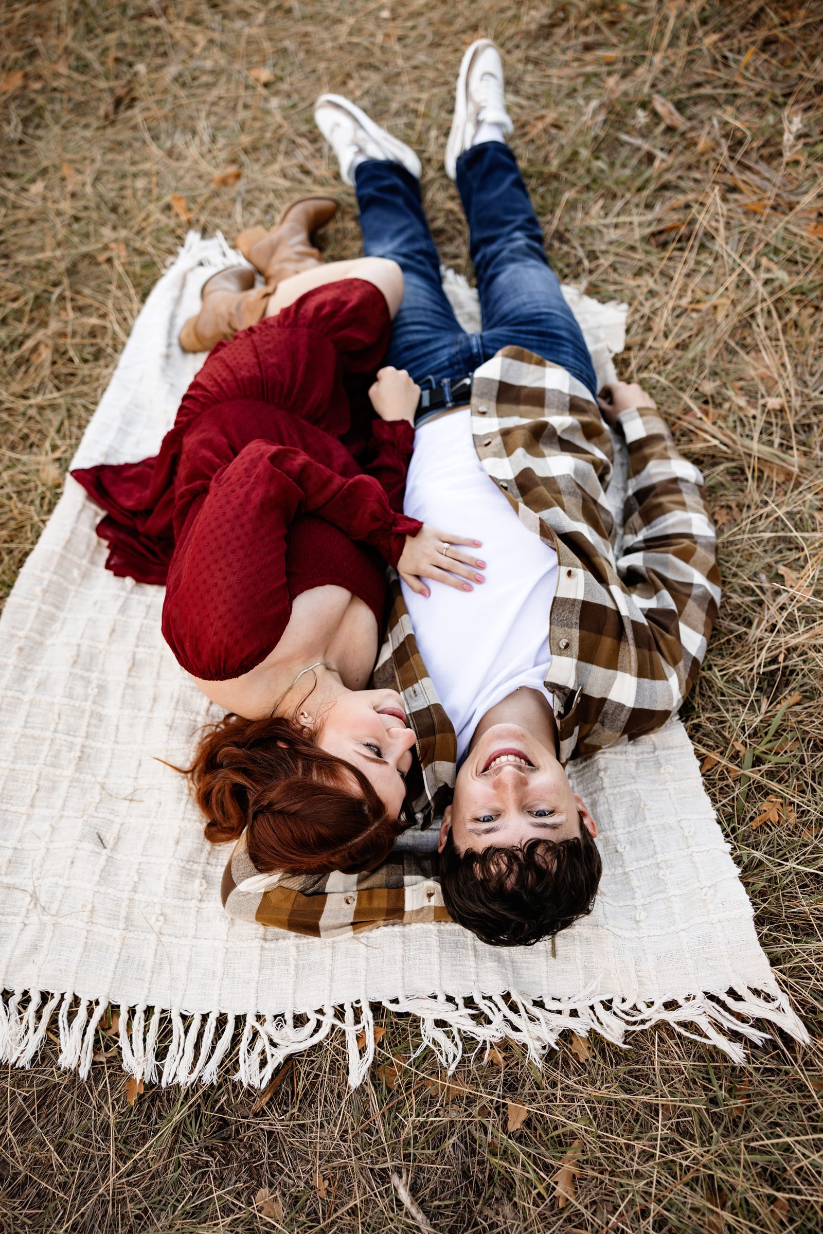 Fall Engagement Photos in Colorado Springs couple lying on a blanket, smiling and cuddling in soft autumn tones