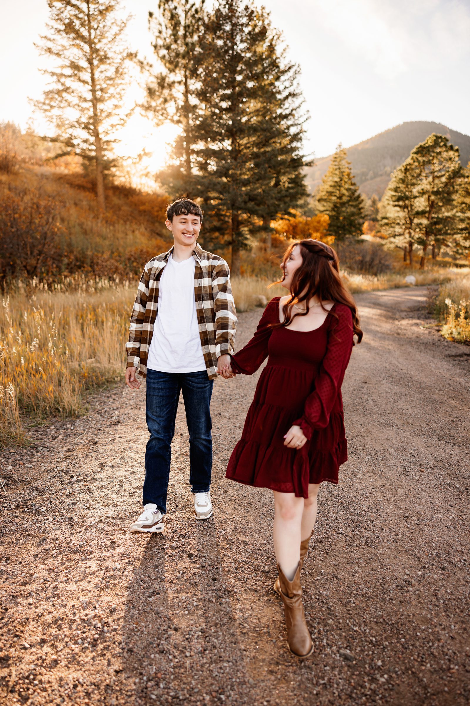 Fall Engagement Photos in Colorado Springs playful couple walking and laughing on a tree-lined path