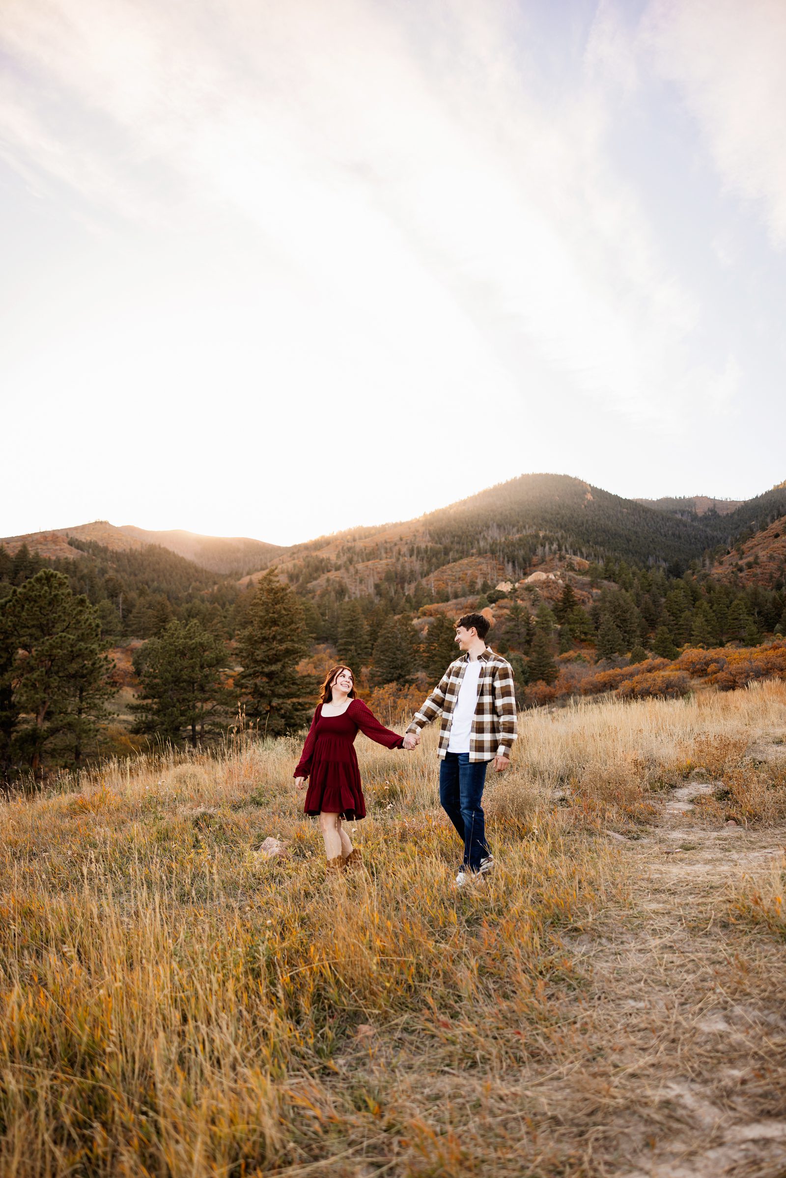 couple walking through a mountain field with autumn colors