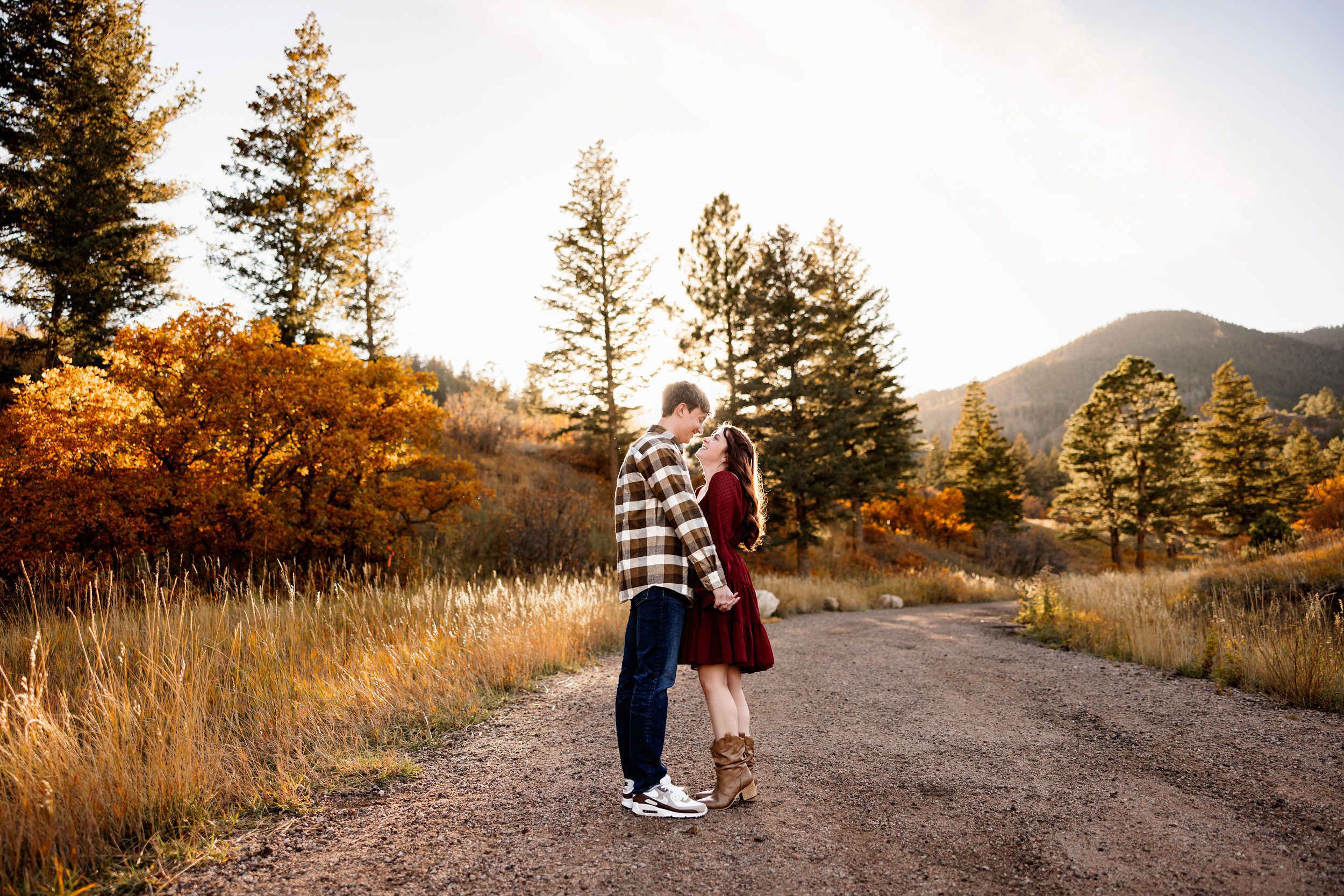 Fall Engagement Photos in Colorado Springs couple holding hands on a scenic dirt road with golden fall colors