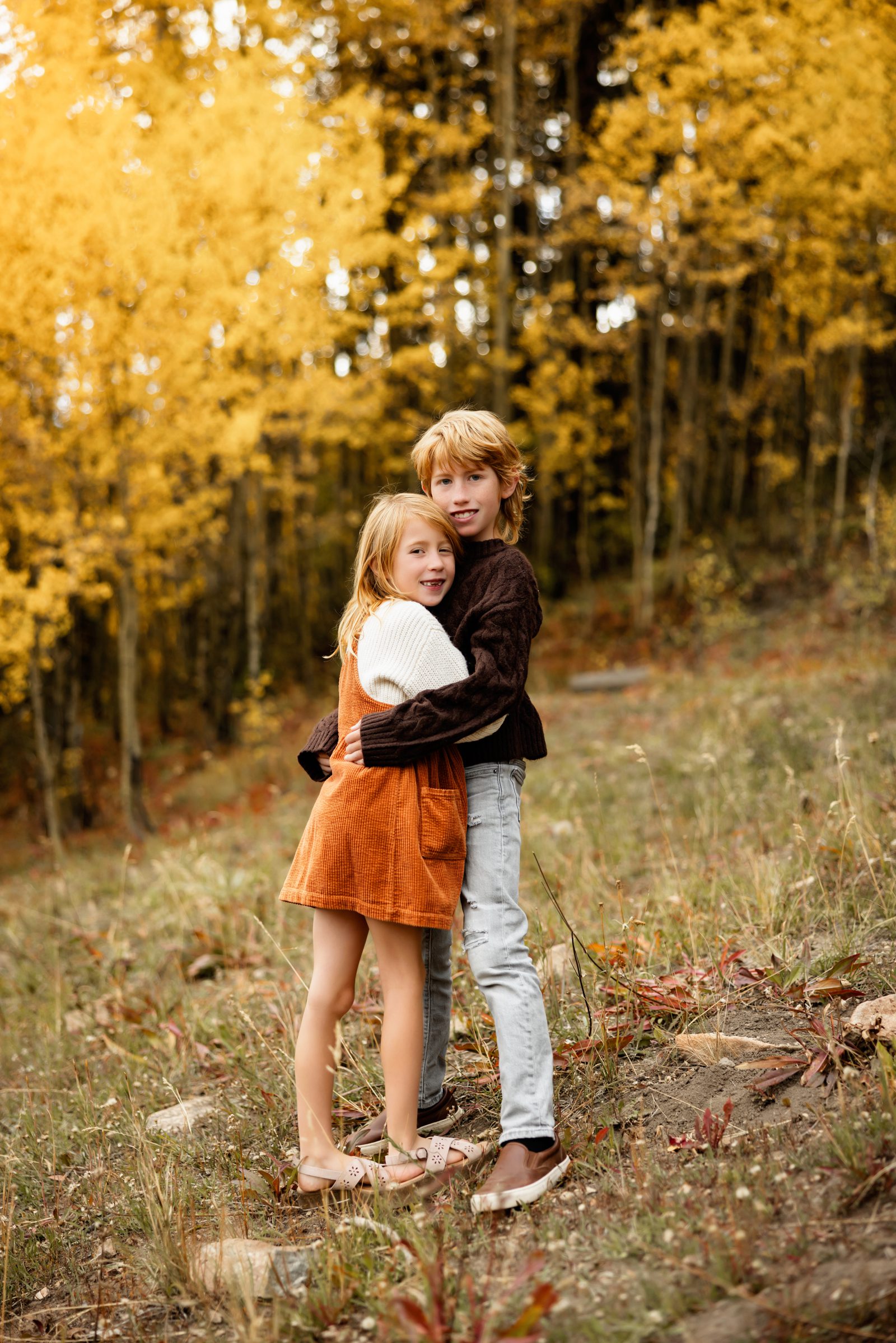 Fall Family Photos in Breckenridge of siblings hugging in front of vibrant yellow aspens