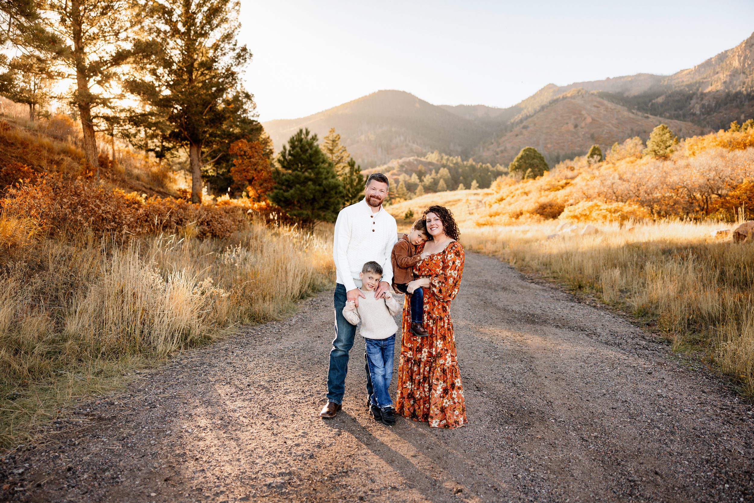 Fall Photo Session in Colorado Springs with family smiling together in warm sunset light and autumn landscape