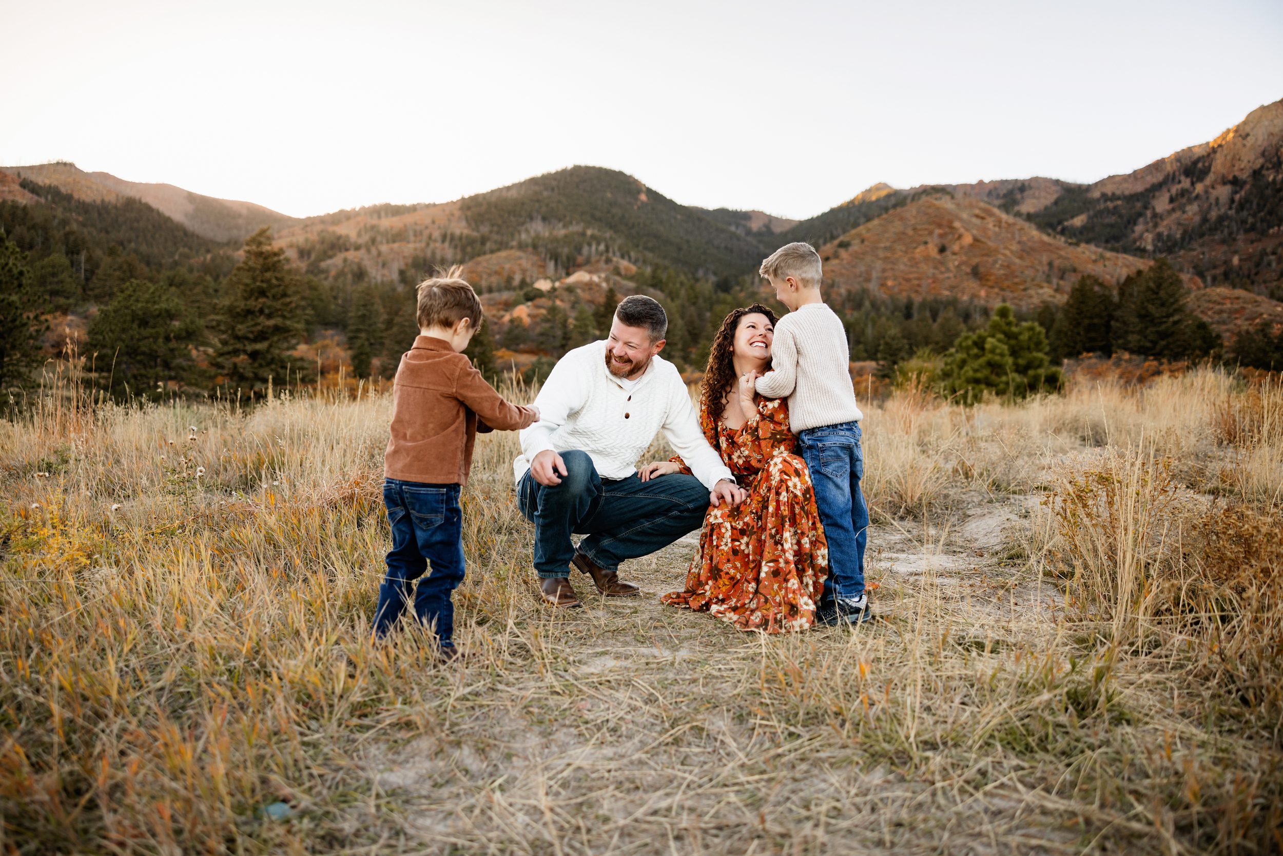 Family sitting in the grass sharing a candid moment surrounded by soft fall tones and rolling hills