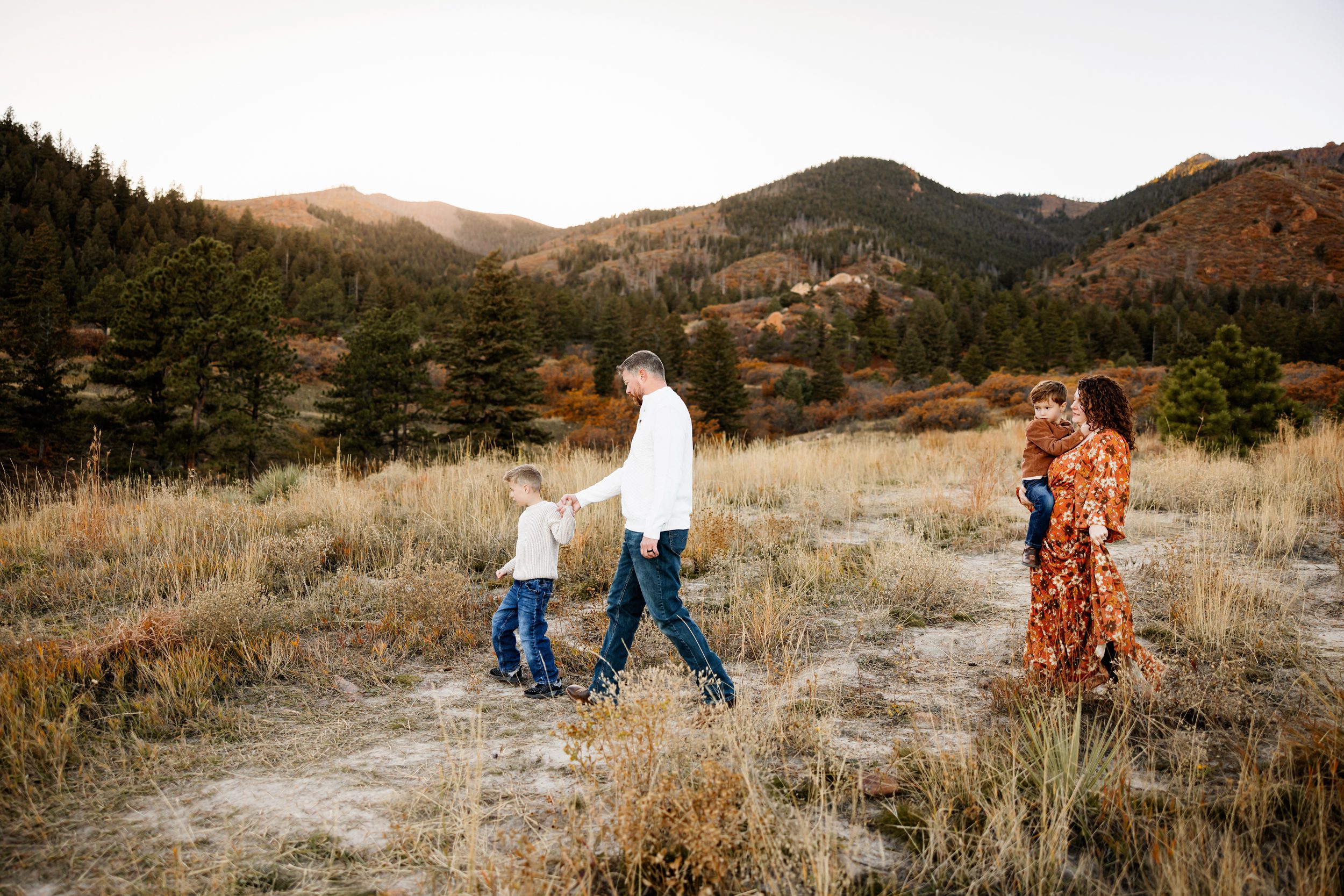 Fall Photo Session in Colorado Springs with family walking together through open field and golden grasses