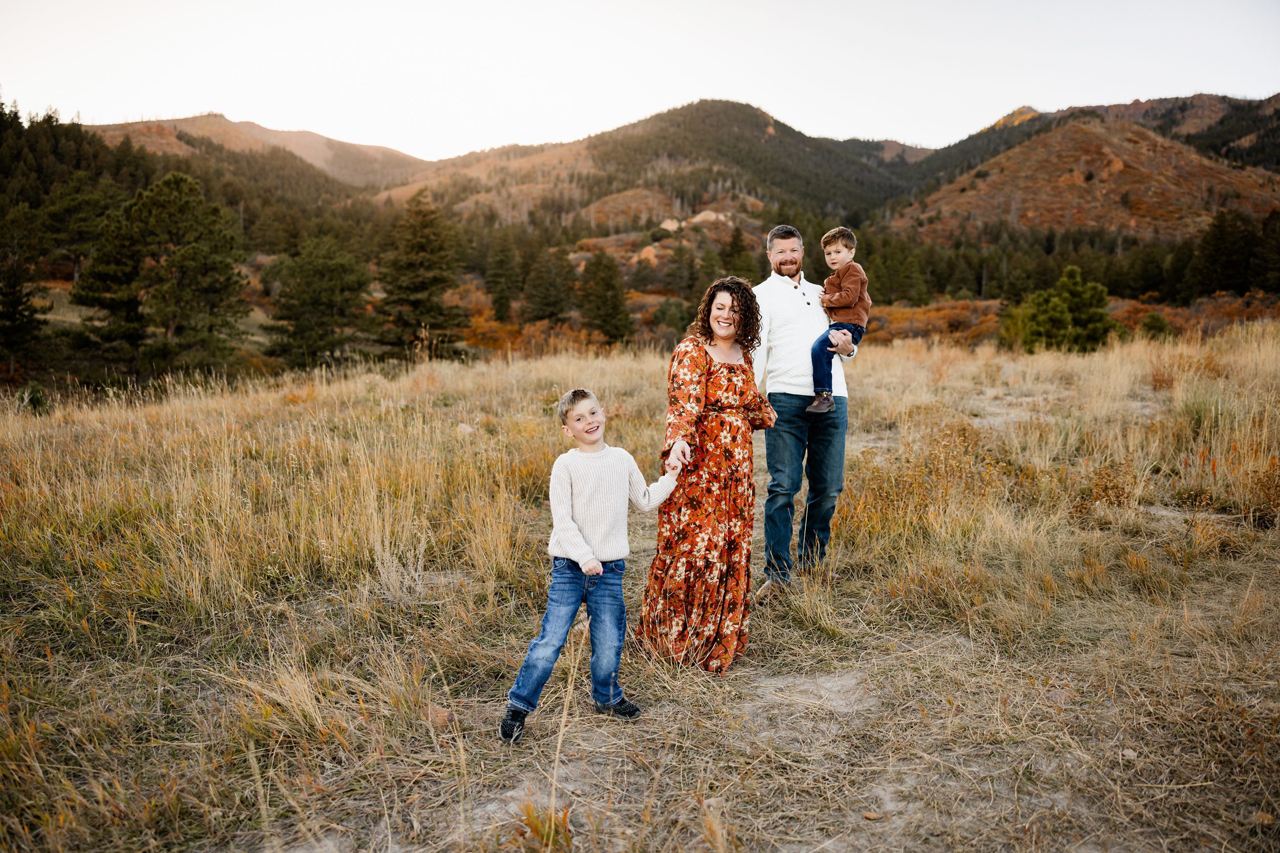 Family walking through a scenic mountain meadow with warm fall colors and soft evening light