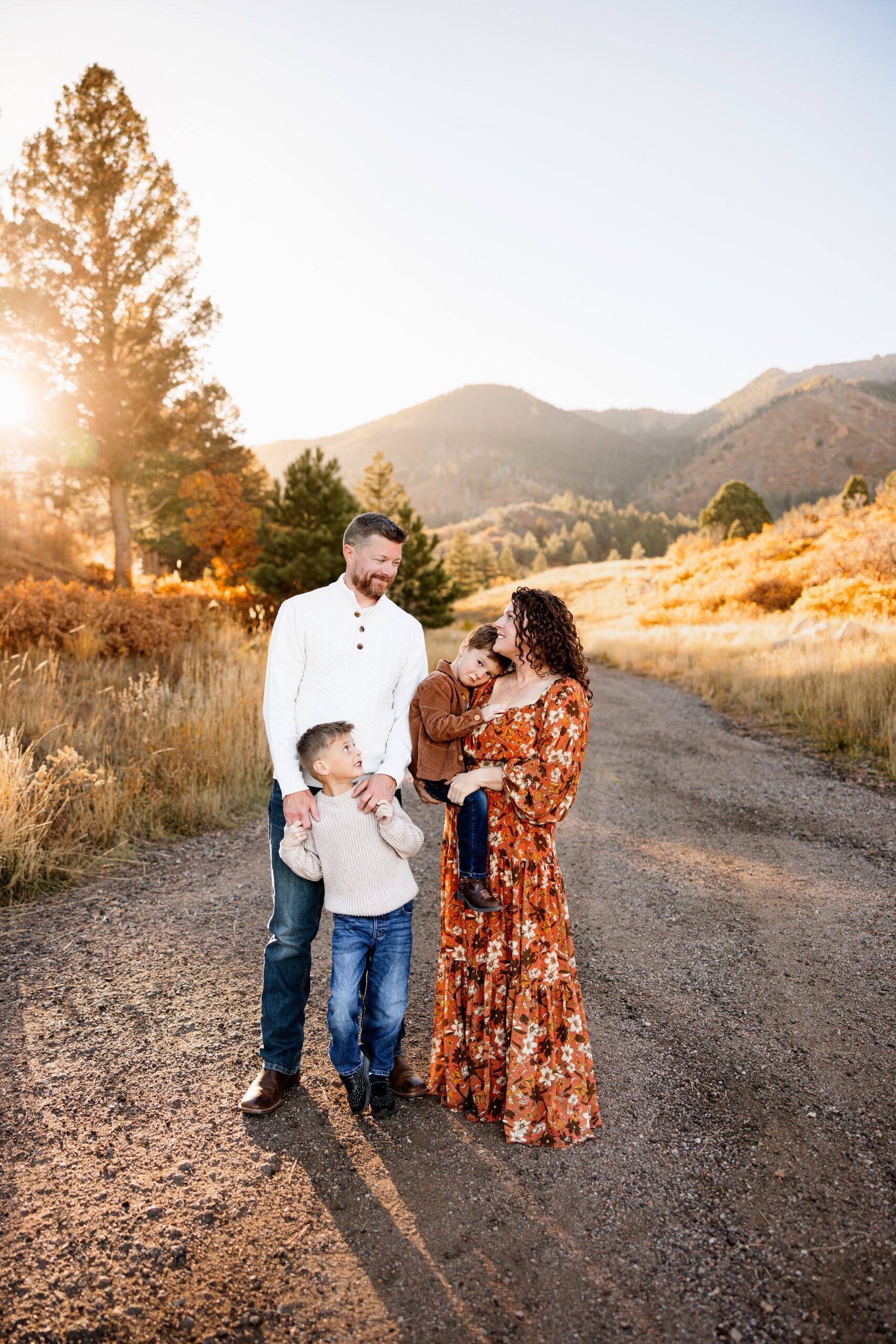 Family standing together on a dirt road with golden fall colors and mountain views in Colorado Springs