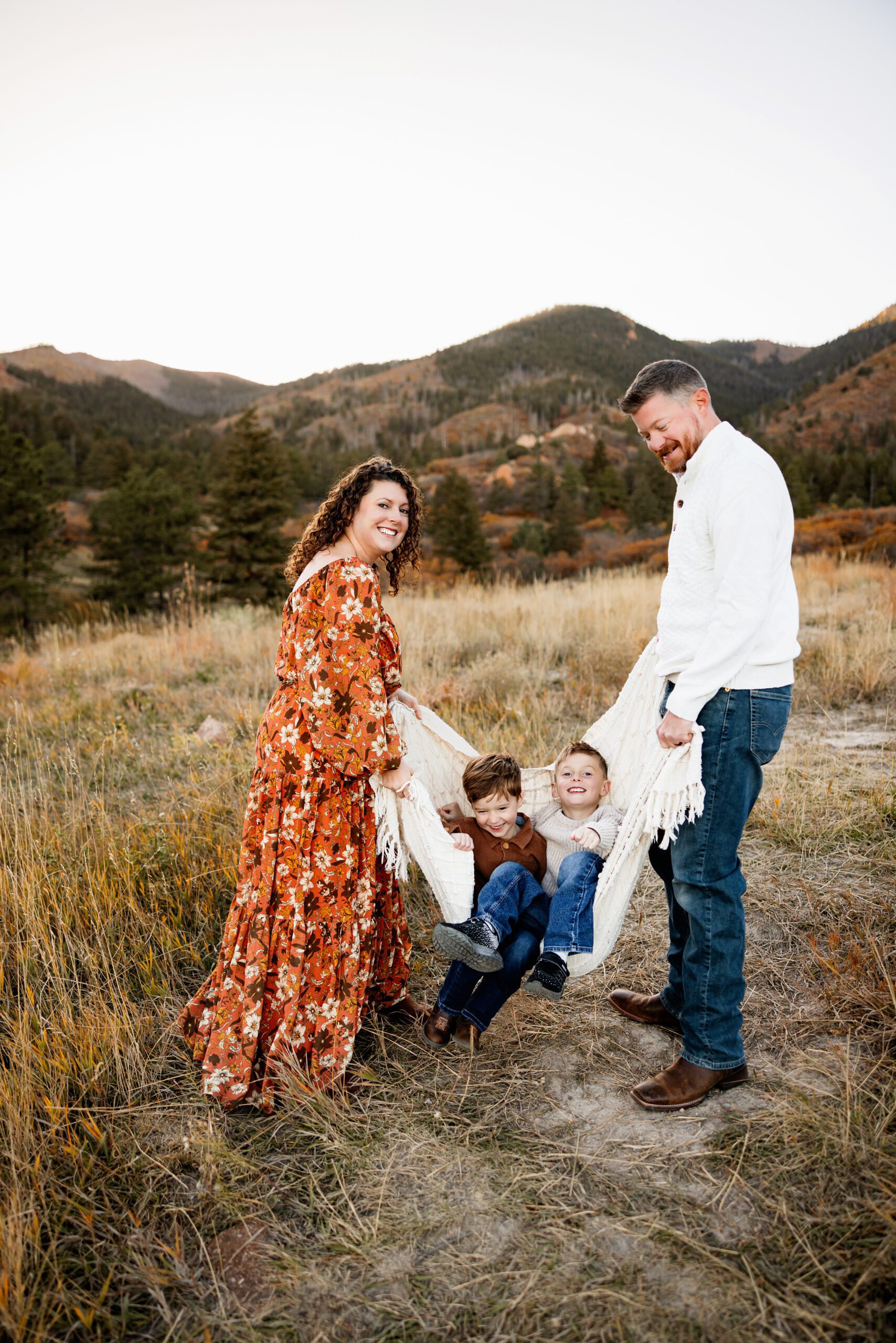 Fall Photo Session in Colorado Springs with playful family moment swinging kids in a blanket outdoors