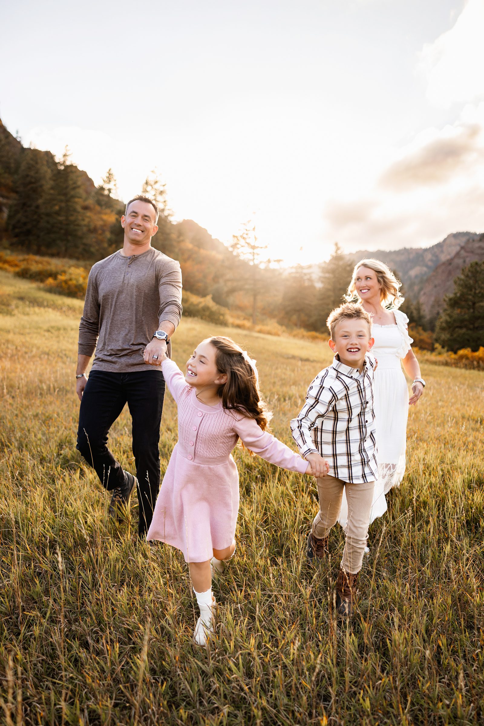 North Cheyenne Canon Family Photos of parents walking hand in hand with their kids through a golden meadow at sunset