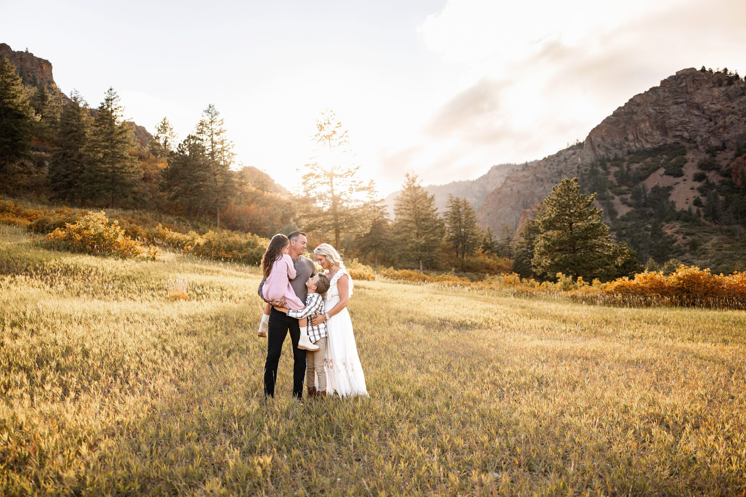 North Cheyenne Canon Family Photos of parents holding their two kids in a glowing meadow at sunset