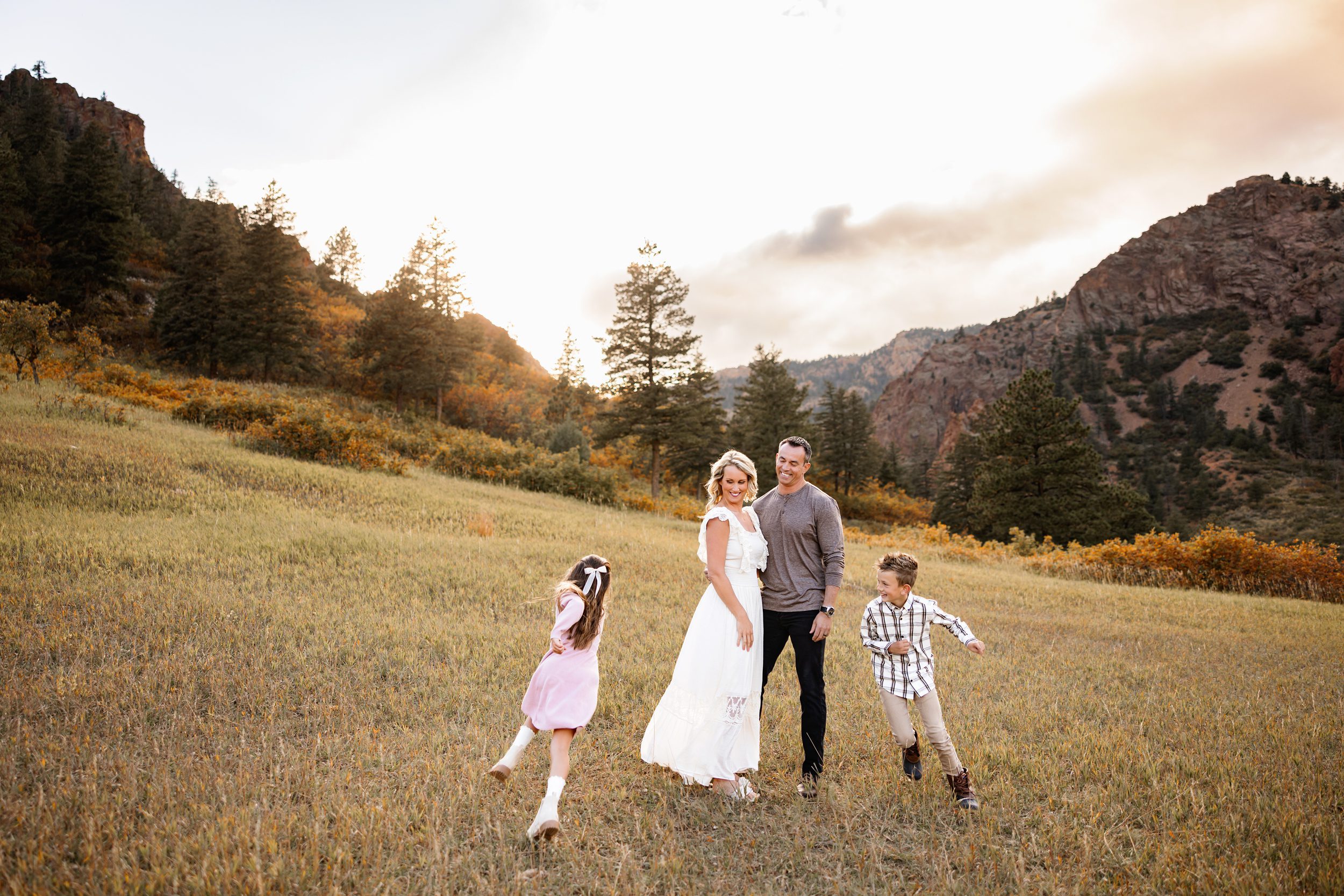 North Cheyenne Canon Family Photos of kids playing while parents laugh in a wide grassy meadow