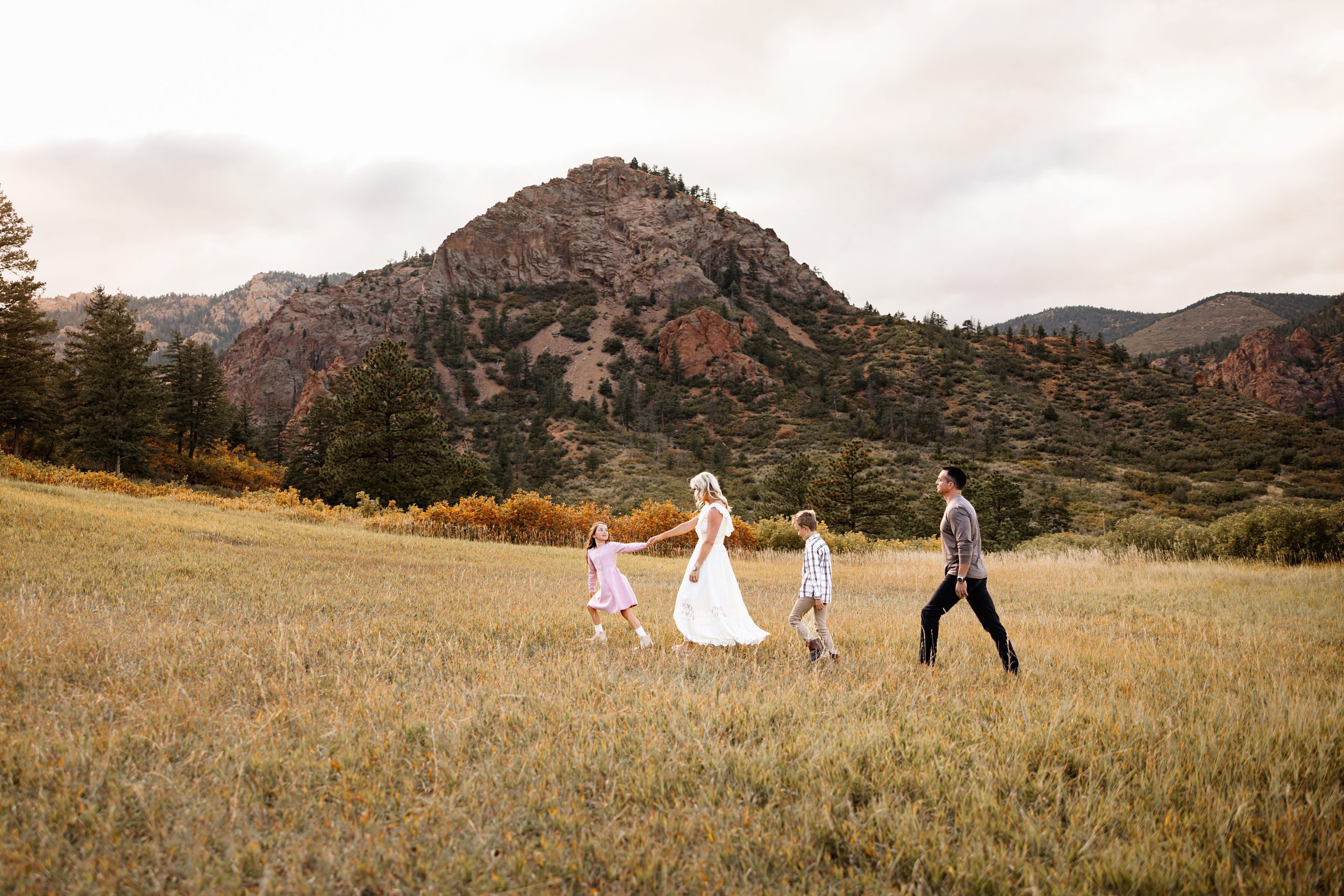 Family walking across an open field with mountain views and fall colors in Colorado
