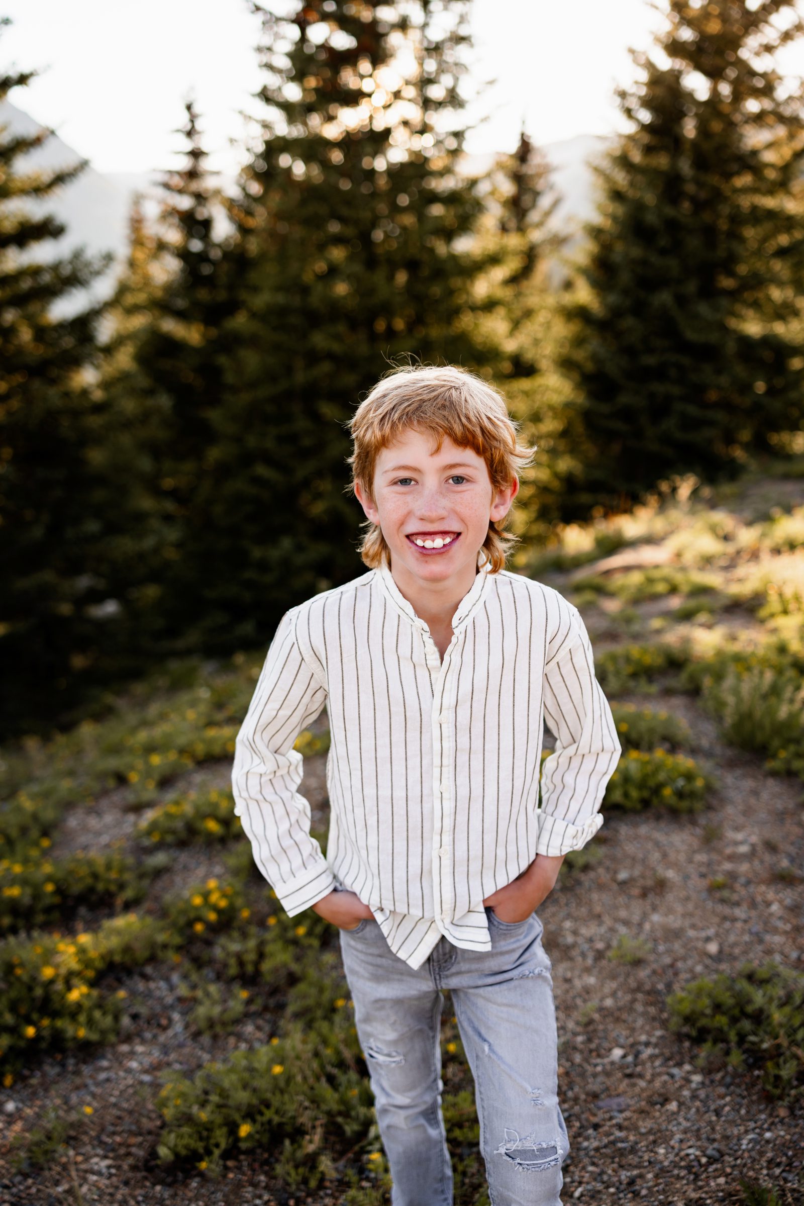 Portrait of a smiling boy during Family Photos in Breckenridge surrounded by pine trees and warm evening light
